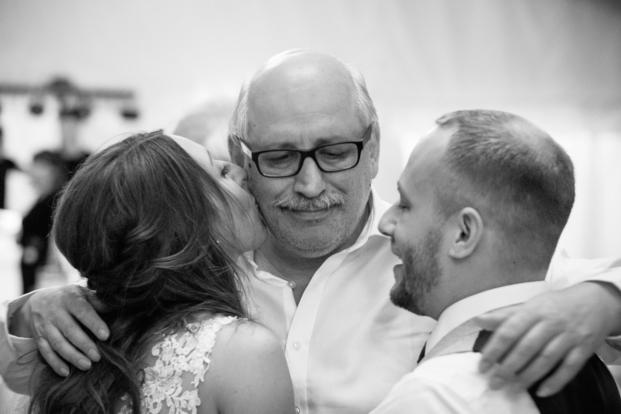  father of the Bride hugs the Groom and Bride 