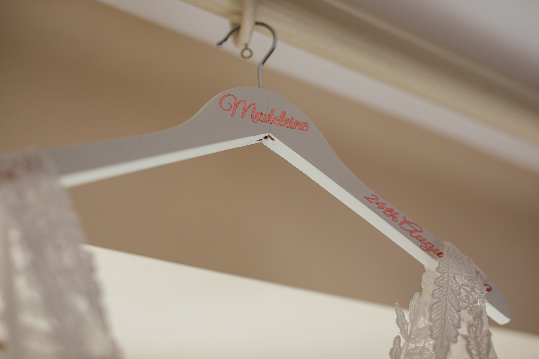  Bride’s dress hangs up on a clothes hanger showing her name 