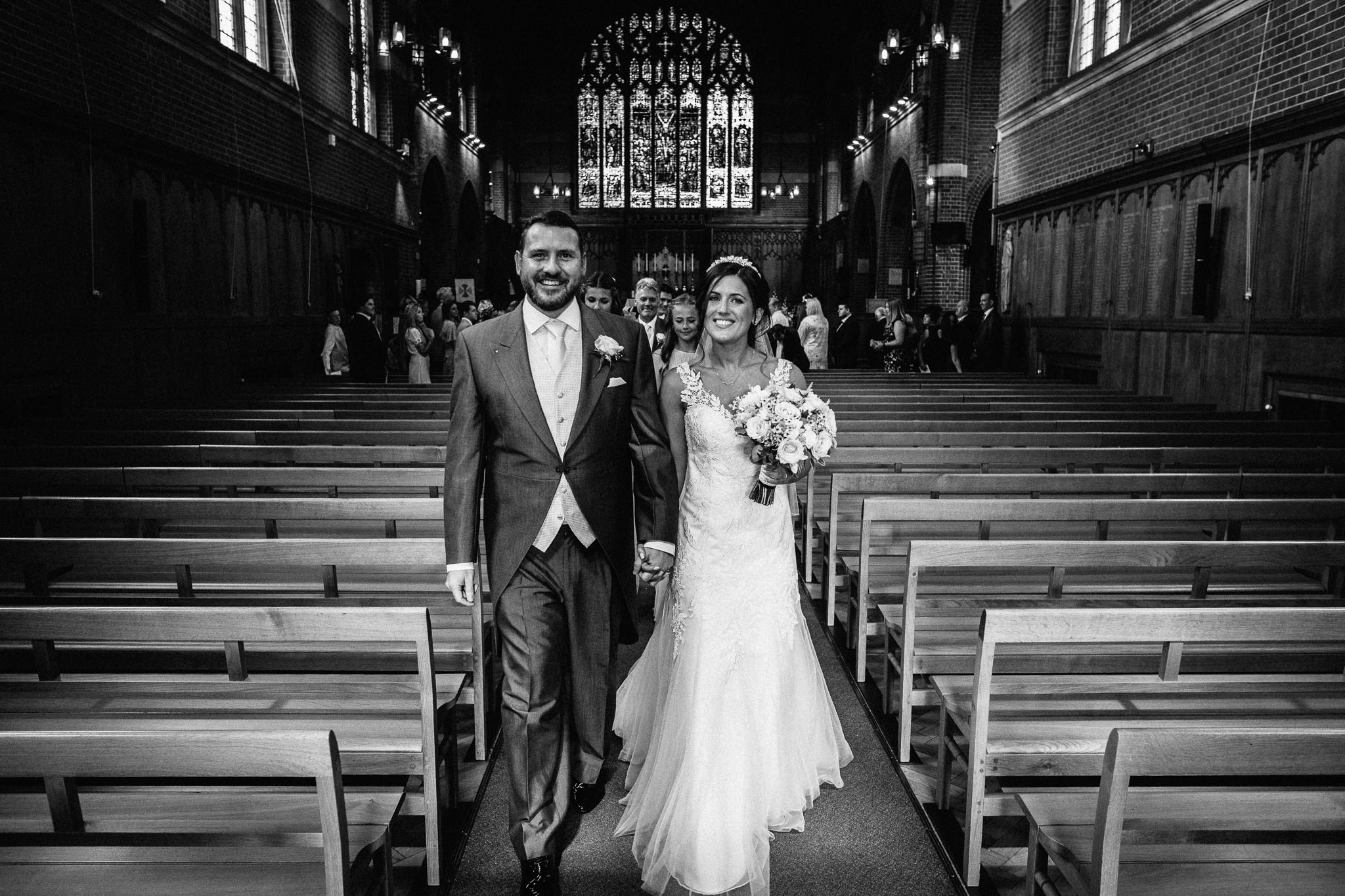  Bride and Groom walk up the aisle  at the Chapel of St Luke at Epsom College 