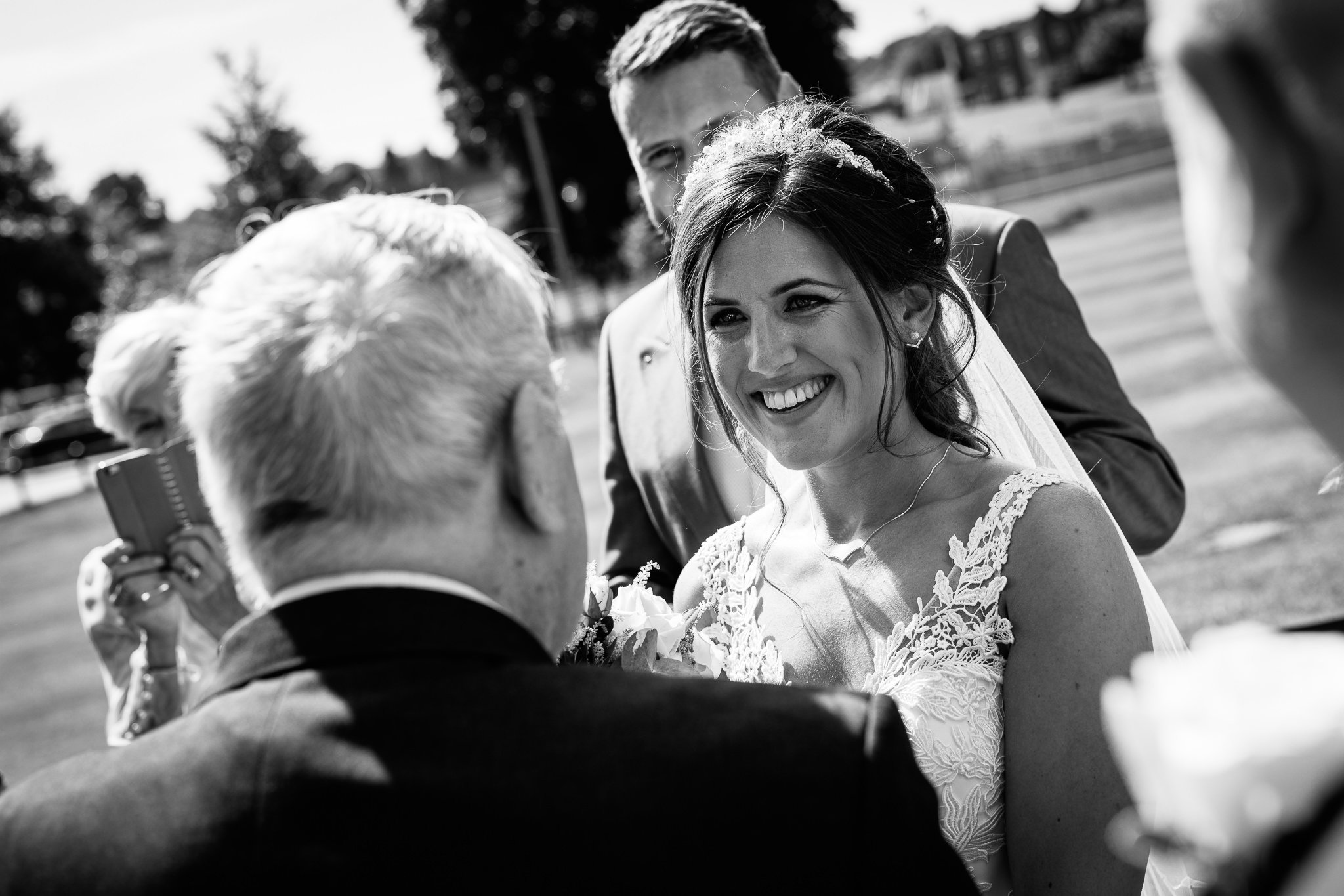  Bride smiling at wedding guest outside  the Chapel of St Luke at Epsom College 
