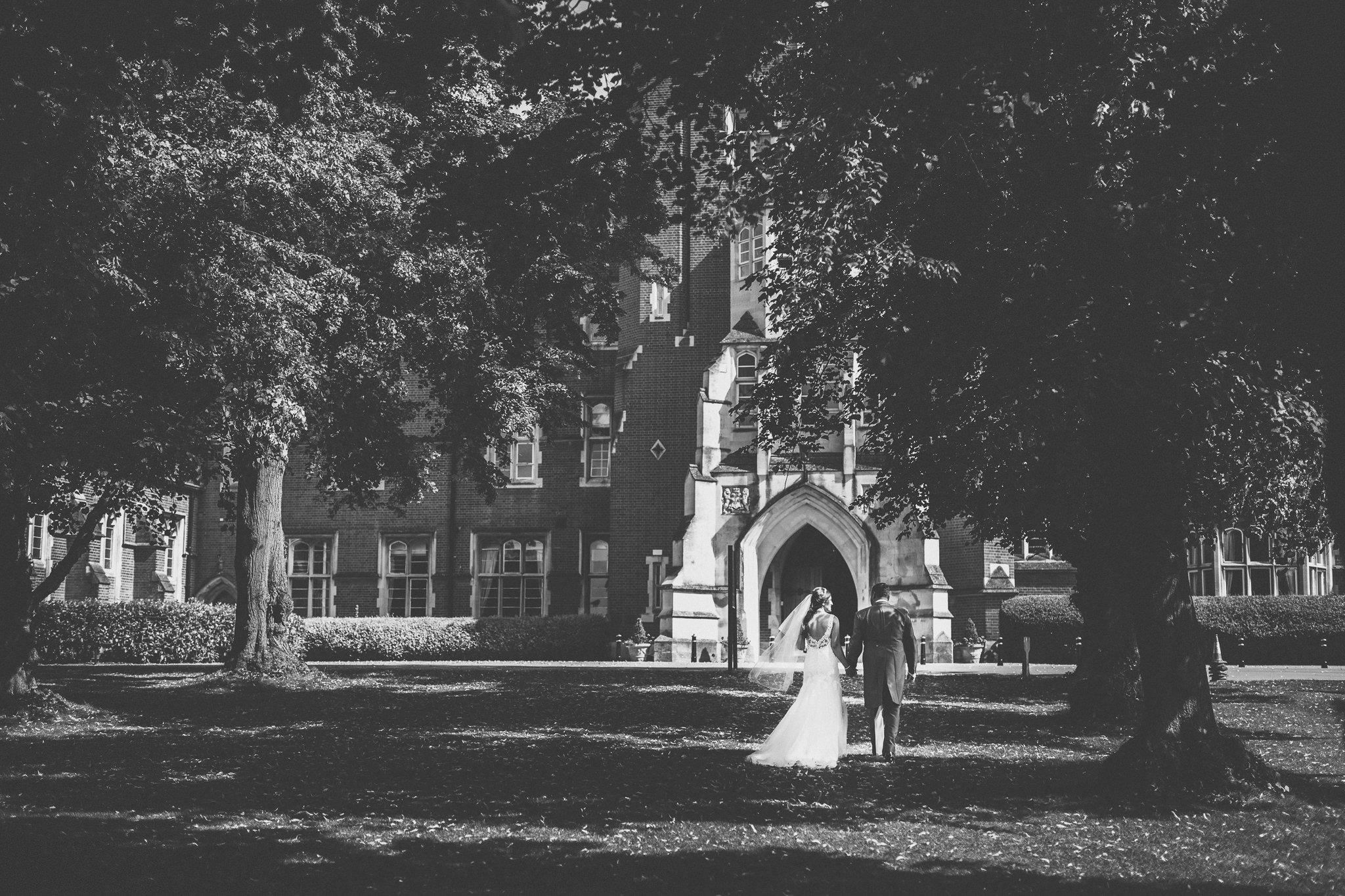  Bride and Groom holding hands walking on the grounds of Epsom college 