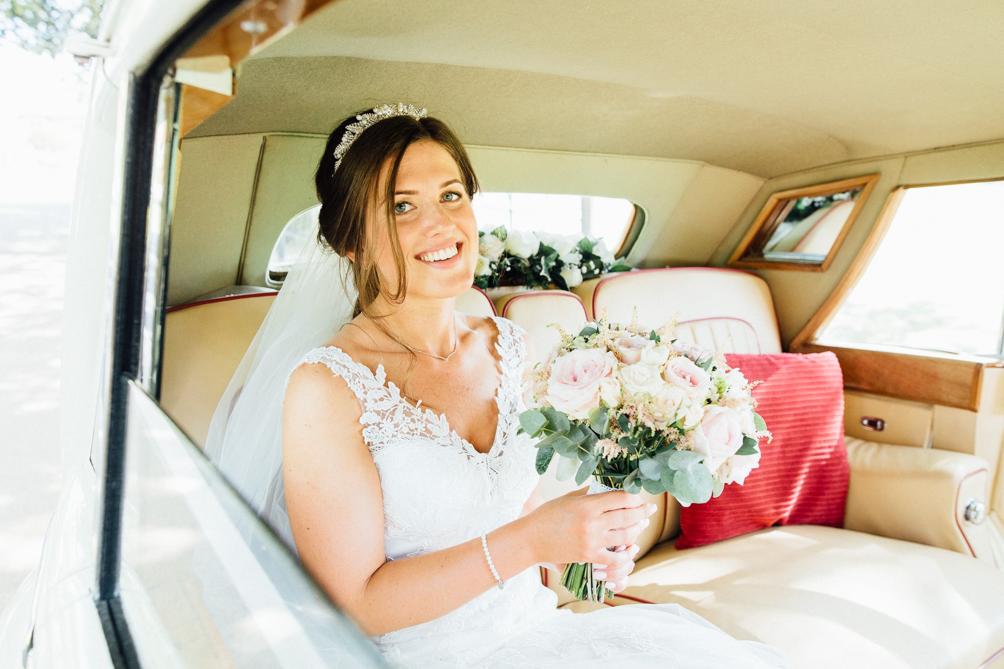  Bride smiling sitting in wedding car 