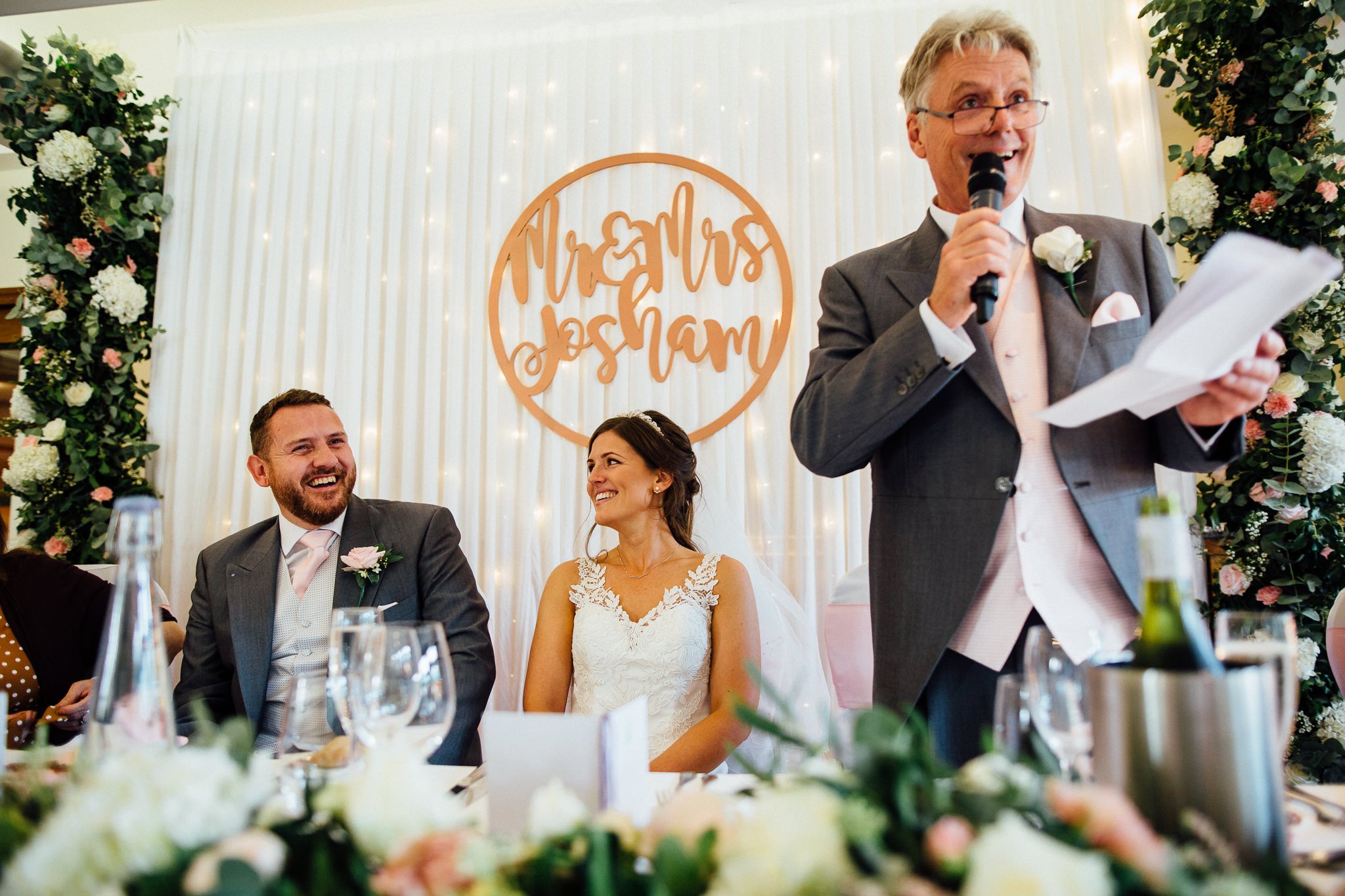  Bride and Groom laugh at the Father of the Bride’s speech  at Walton Heath Golf Club Surrey 