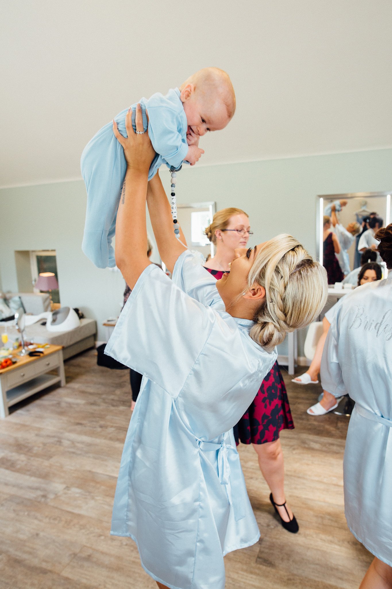  Baby being held aloft by a bridesmaid 