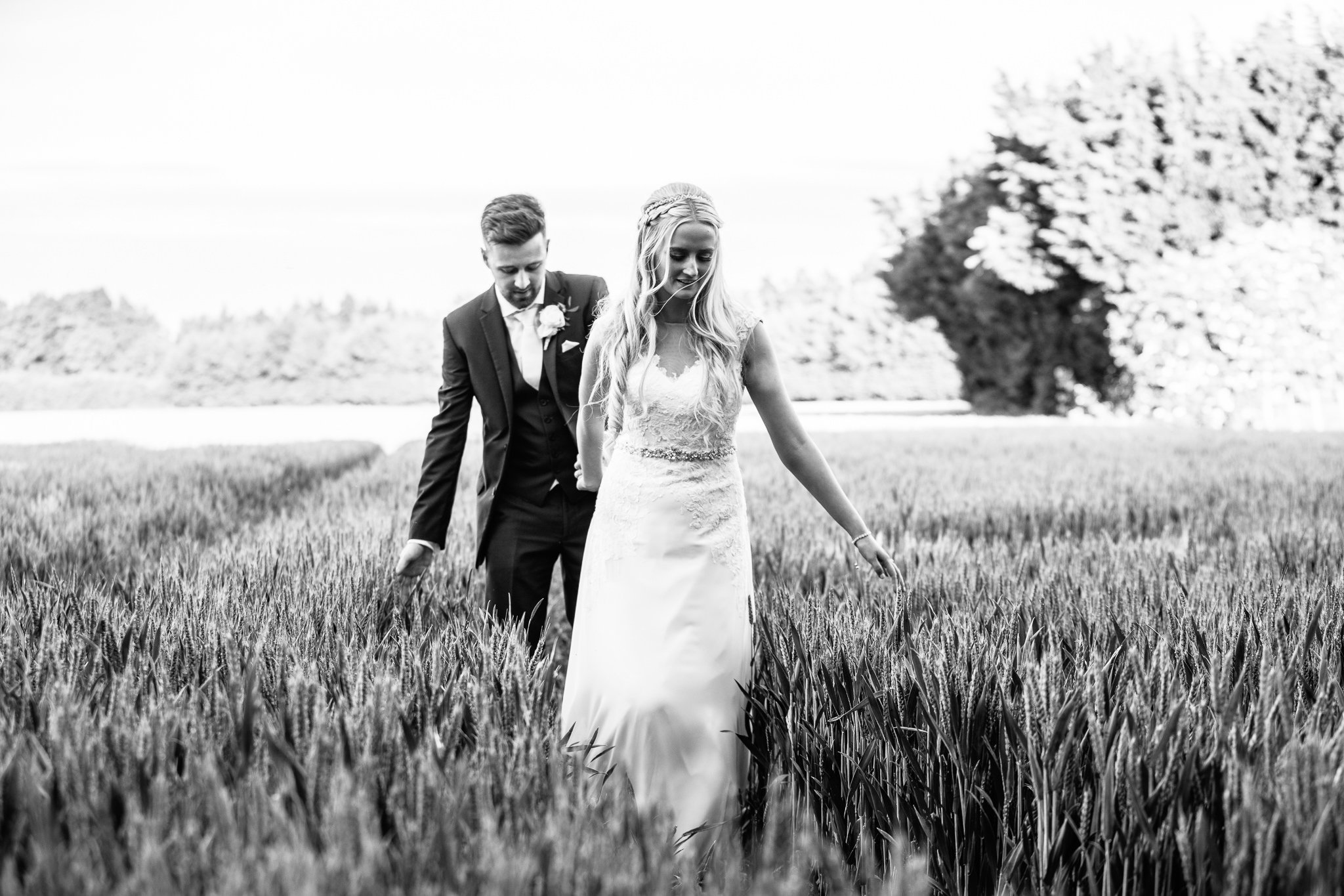  Bride and Groom walking through a wheat field at Winters Barns Wedding Venue Kent 