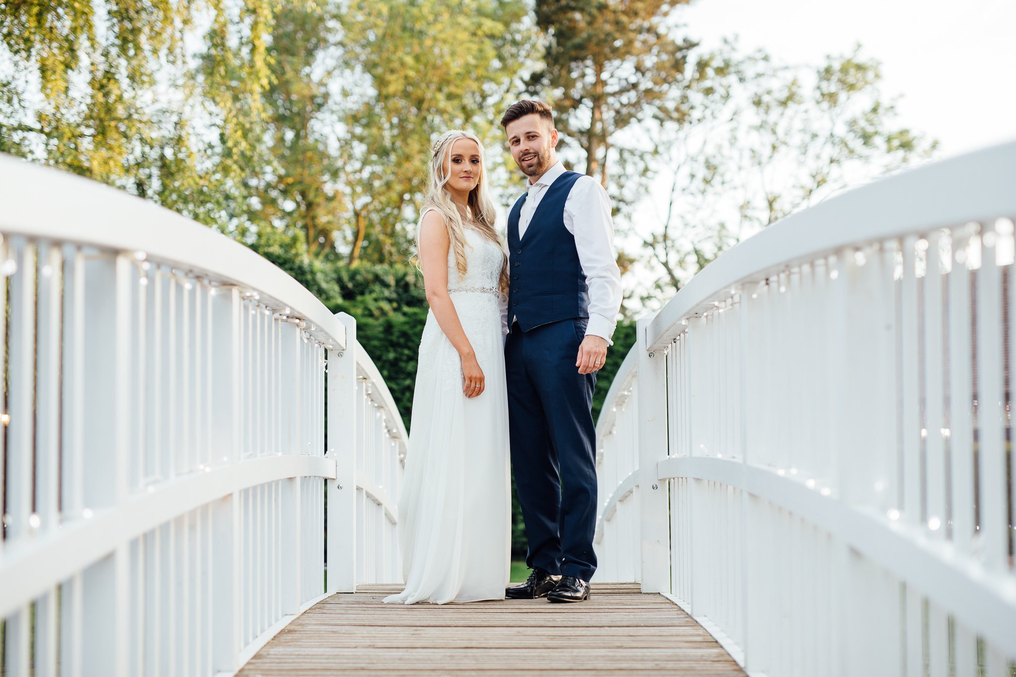  Bride and Groom stand on the white Bridge in the courtyard at Winters Barns Wedding Venue Kent at the end of their wedding day. 