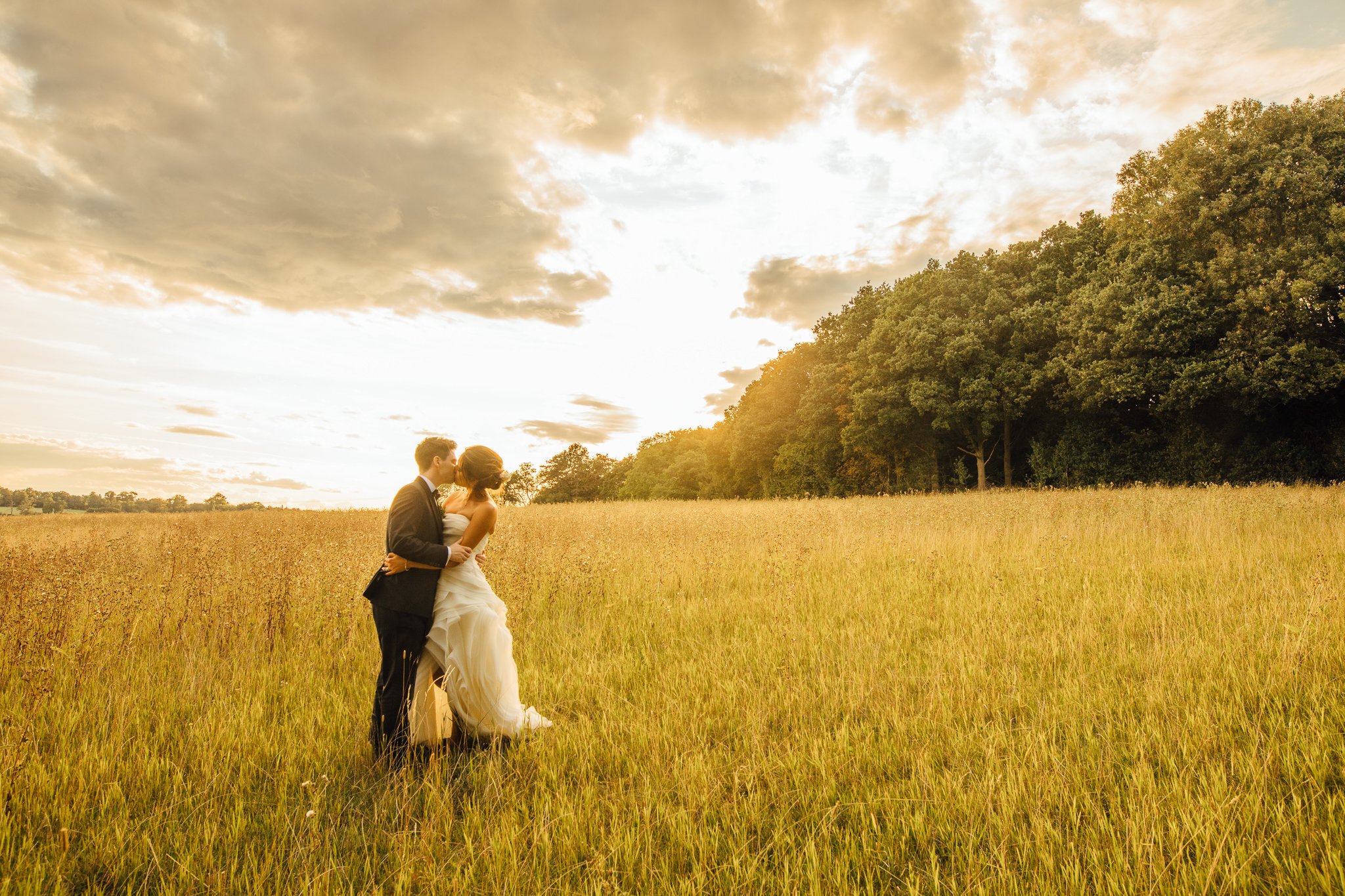  Bride and Groom kiss in a field outside Laura Ashley The Manor Elstree 