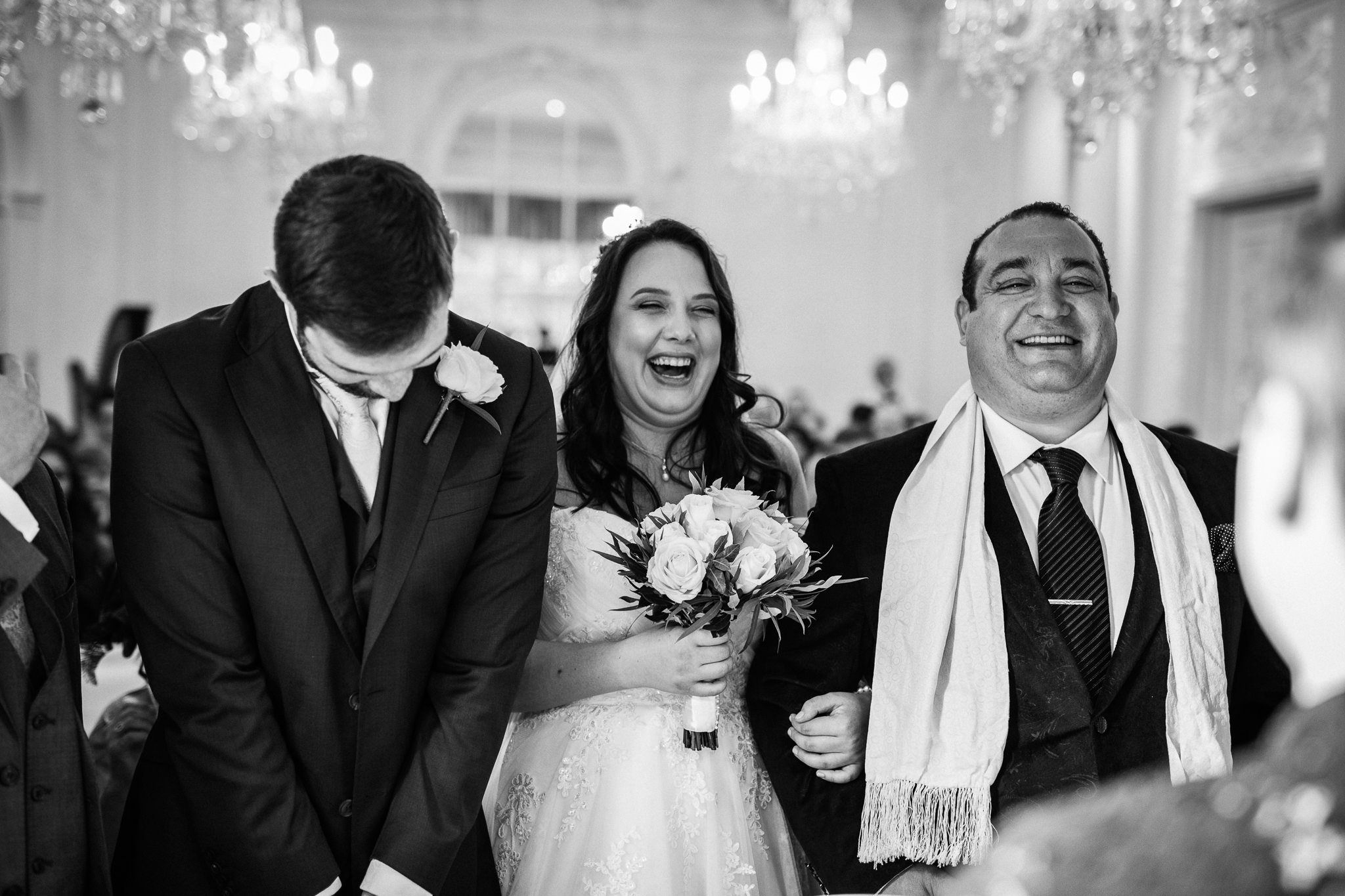  Bride laughing as she stands next to the Groom and her Father 