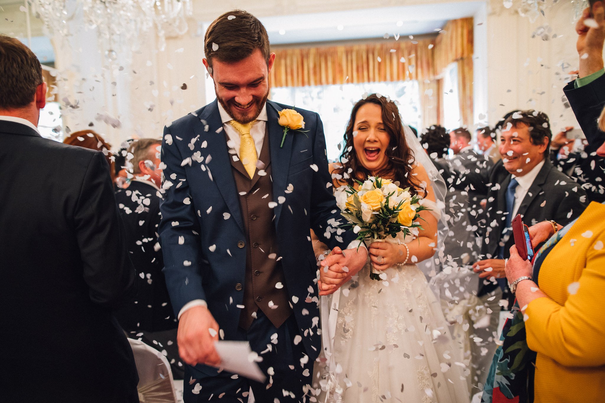  Bride and Groom have confetti thrown at them as they walk down the aisle at Warren House Hotel Kingston upon Thames 