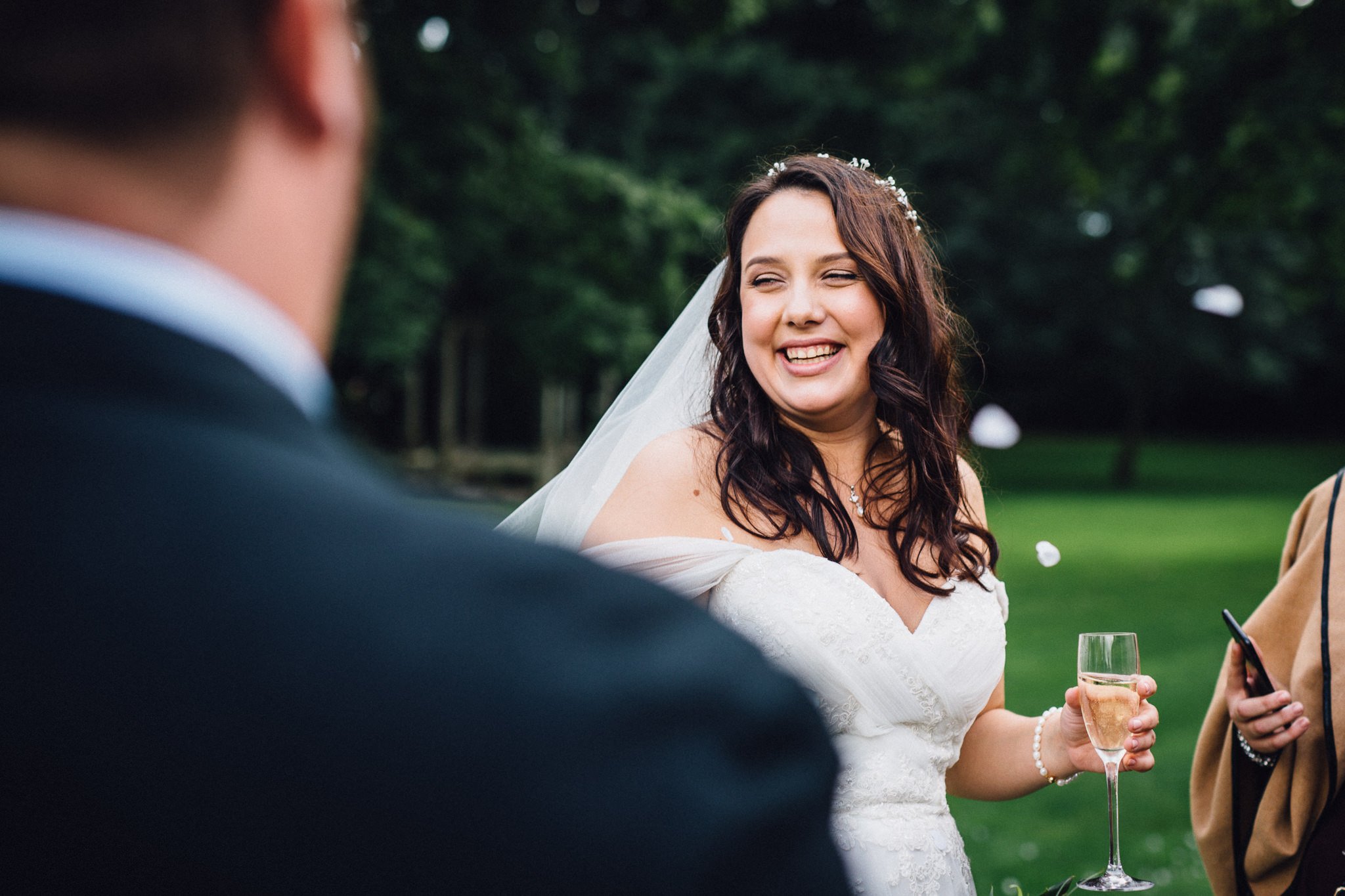  Bride smiling as she holds a glass of champagne at Warren House Hotel Kingston upon Thames 