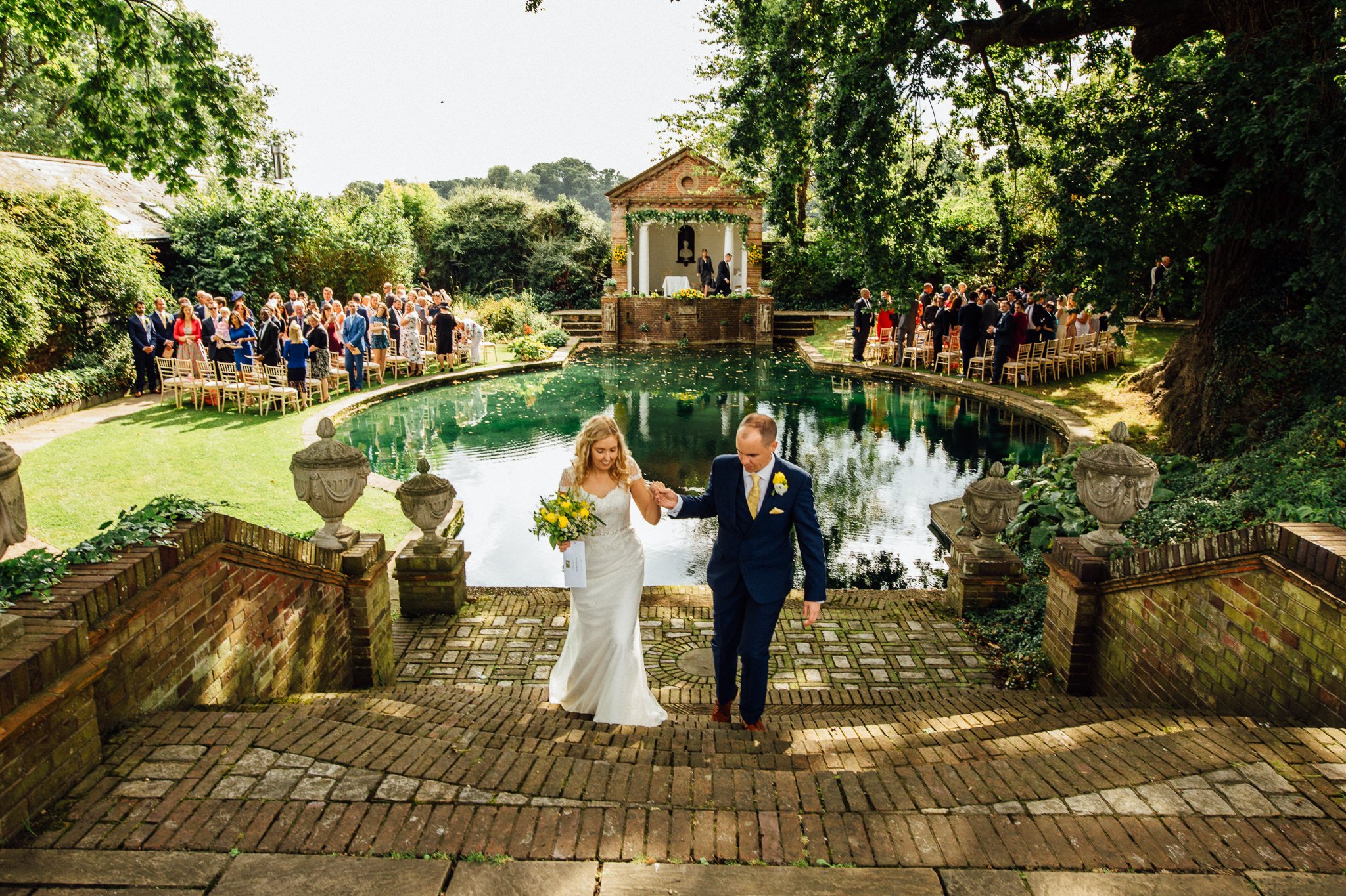  Bride and Groom walk up the steps in front of Temple at Micklefield Hall 