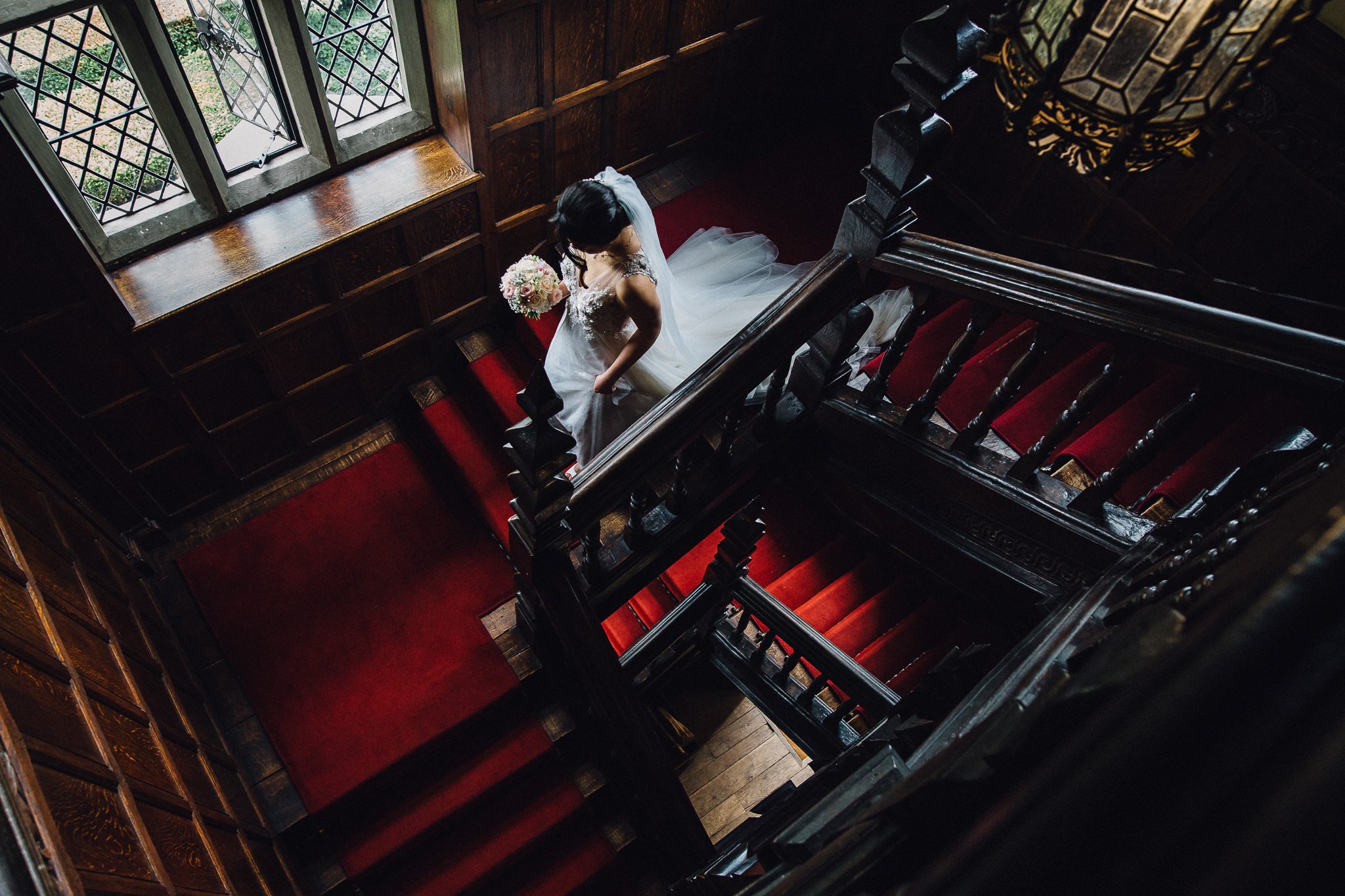  Bride descends an ornate staircase at Great Fosters Egham 