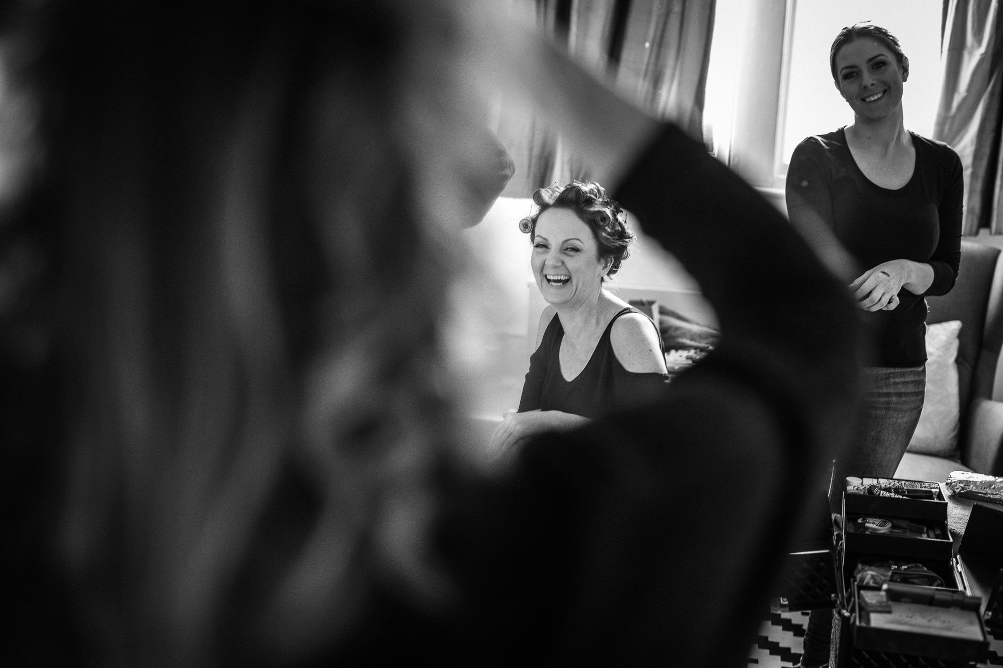  Bride laughing on her wedding day with curlers in her hair. 