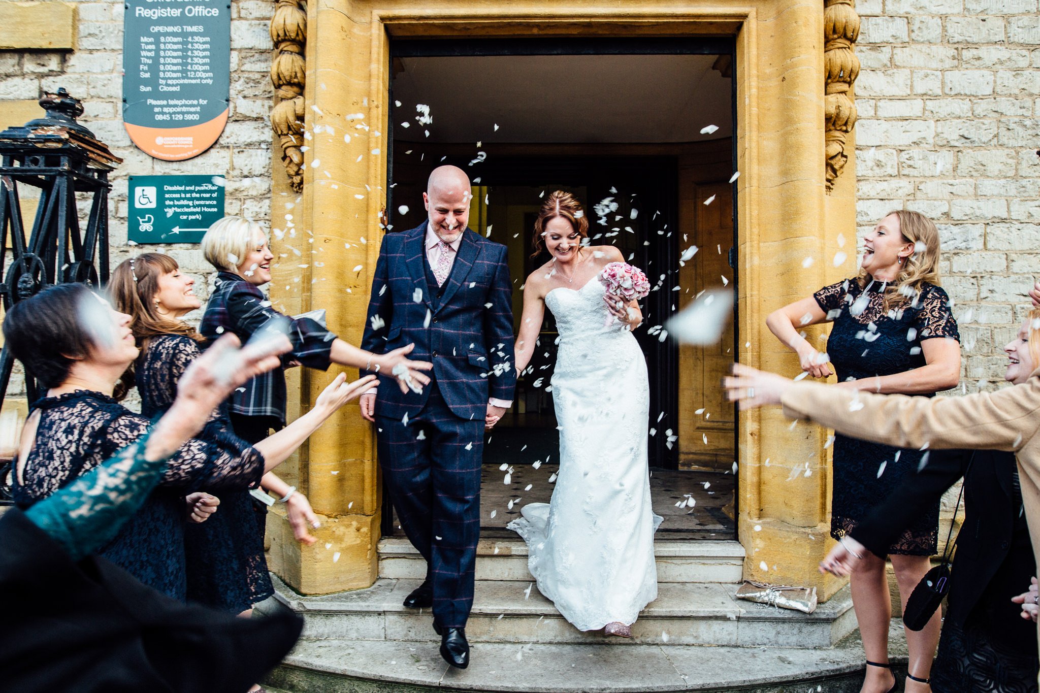  Bride and Groom walk down the steps outside Oxford Register Office as they have confetti thrown at them 
