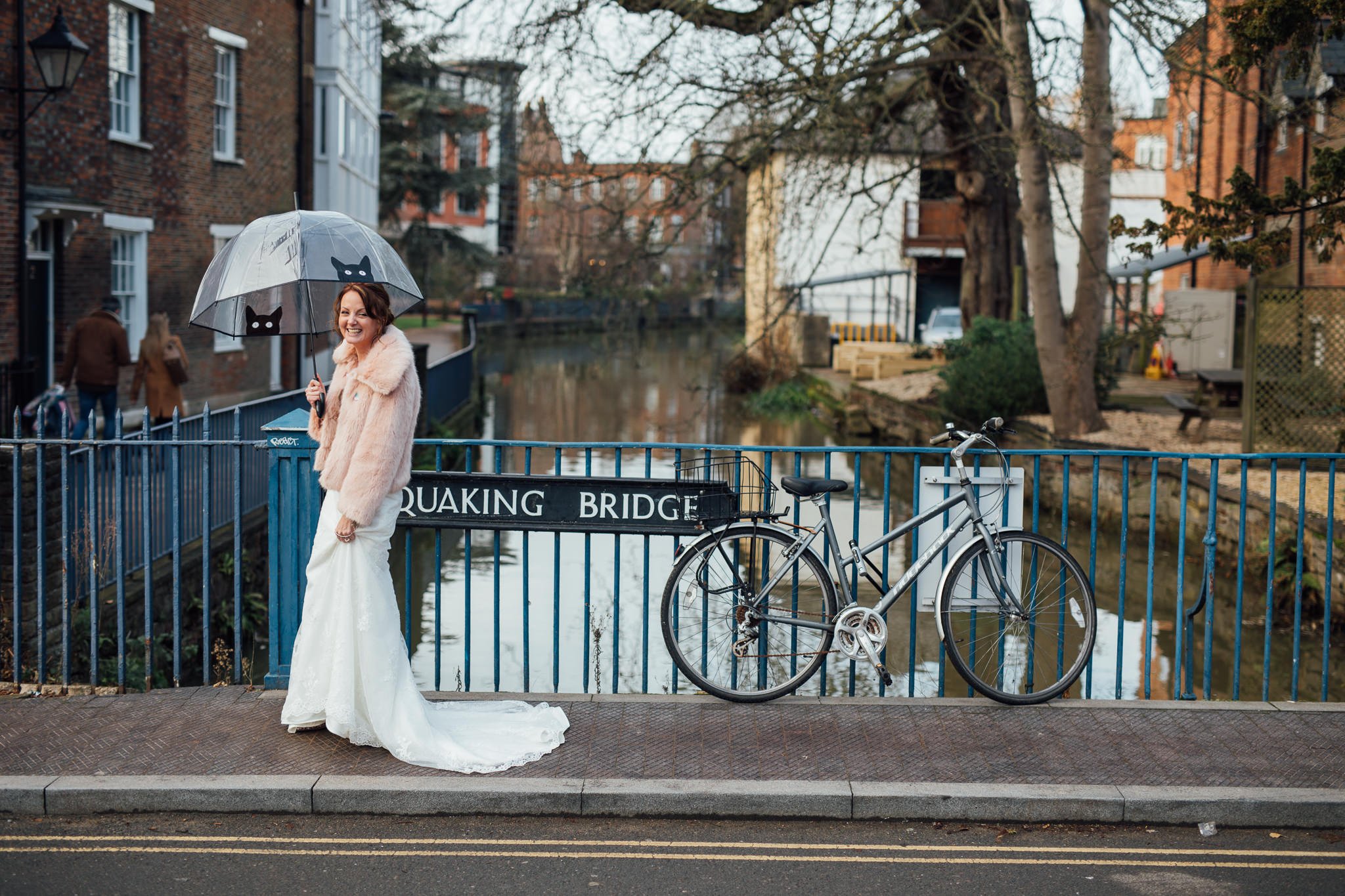  Bride walking across Quasking Bride in Oxford whilst holding an umbrella with a picture of a cat on it. 