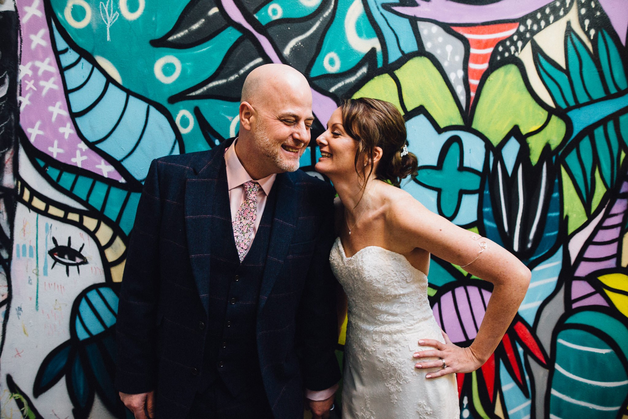  Bride and Groom smiling in front of a wall with graffiti  