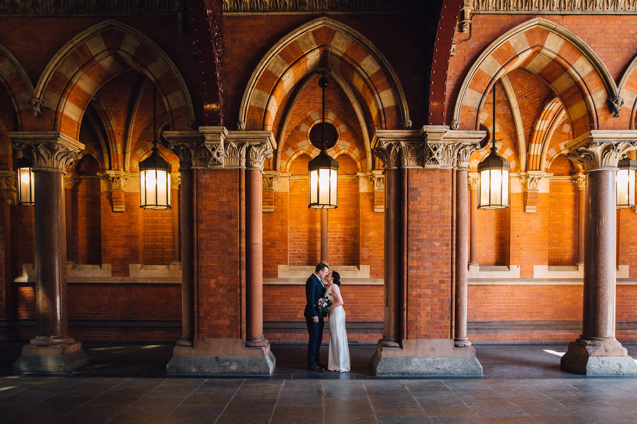  Bride and Groom kissing under an archway at St. Pancras station London 