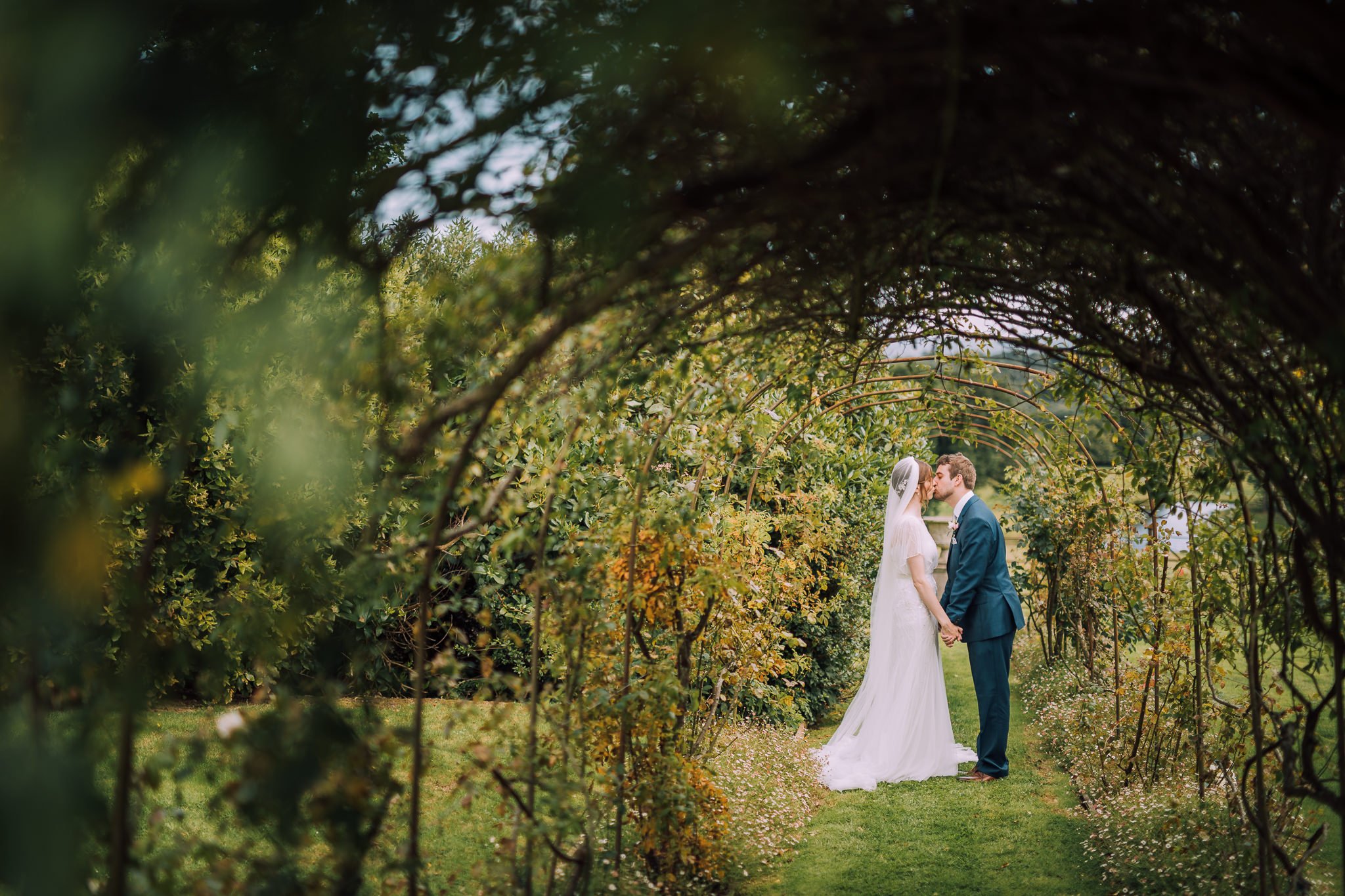  Bride and Groom kiss in the grounds of  Wadhurst castle wedding venue 