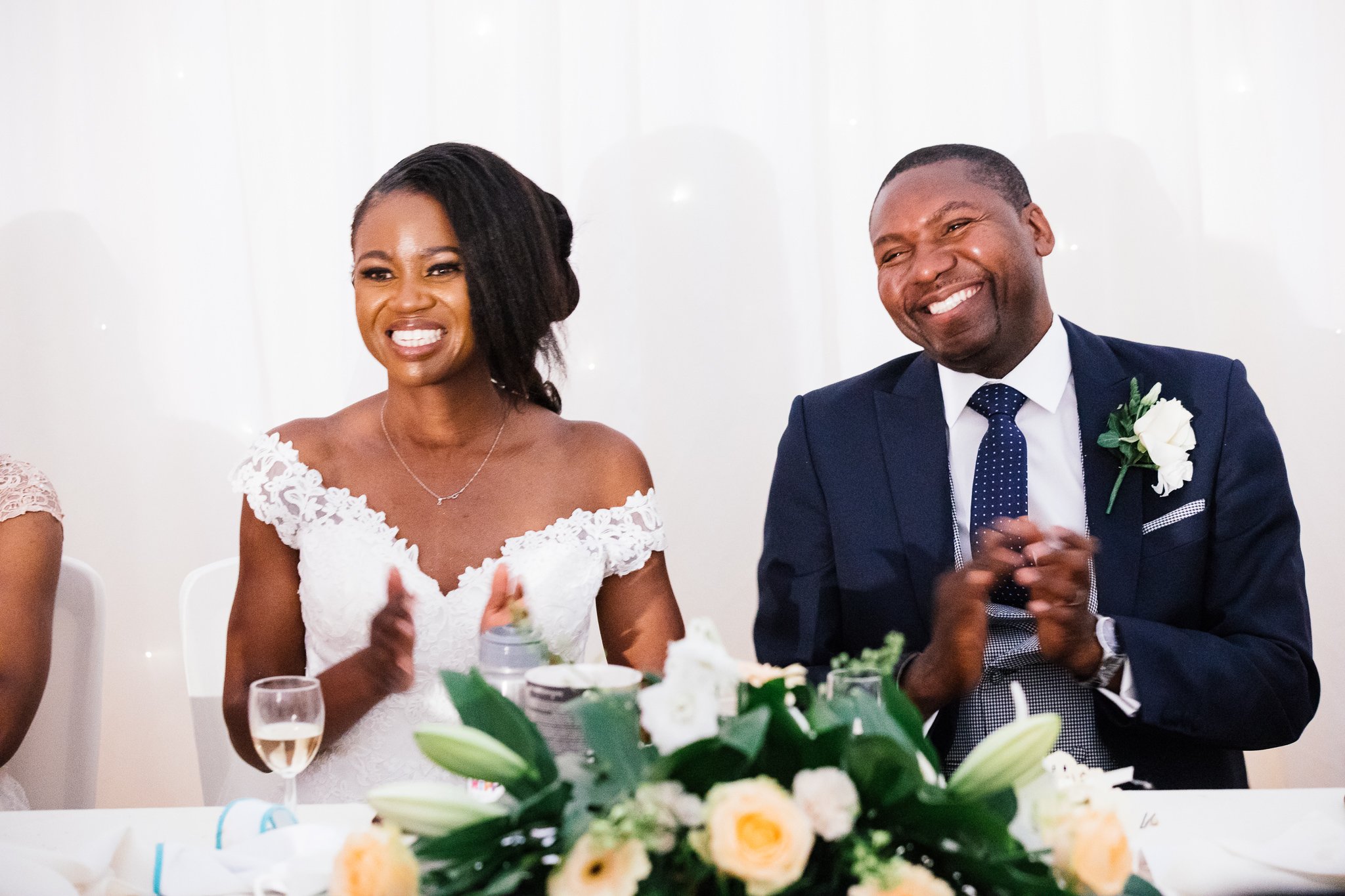  Bride and Groom smiling whilst seated during the speeches 