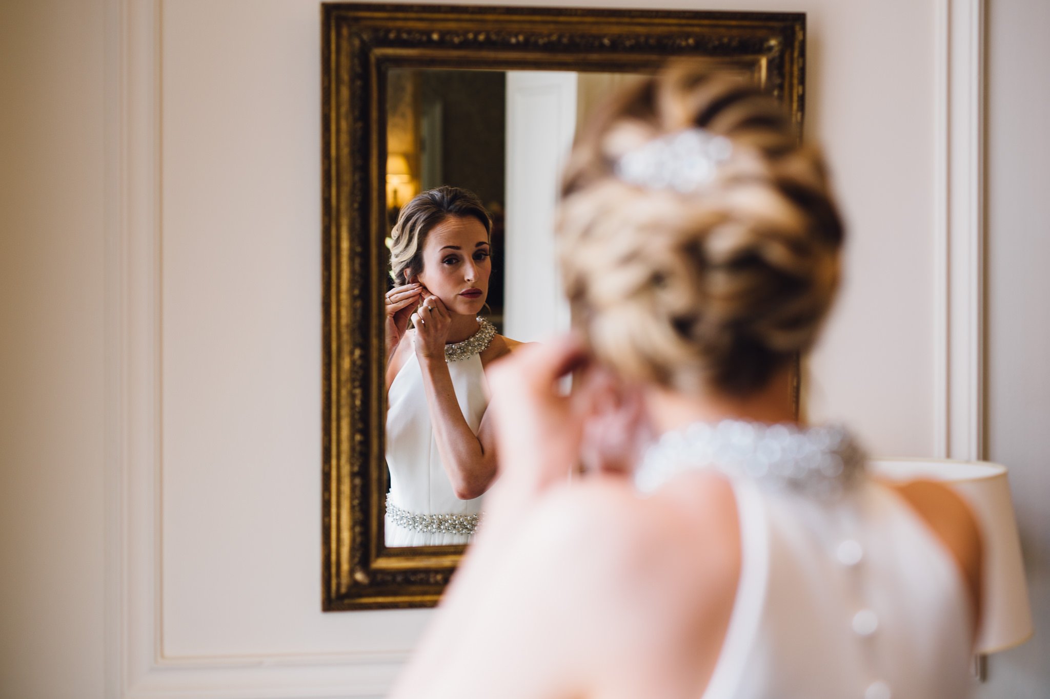  Bride looking in the mirror at The Kensington Hotel as she puts earings on 