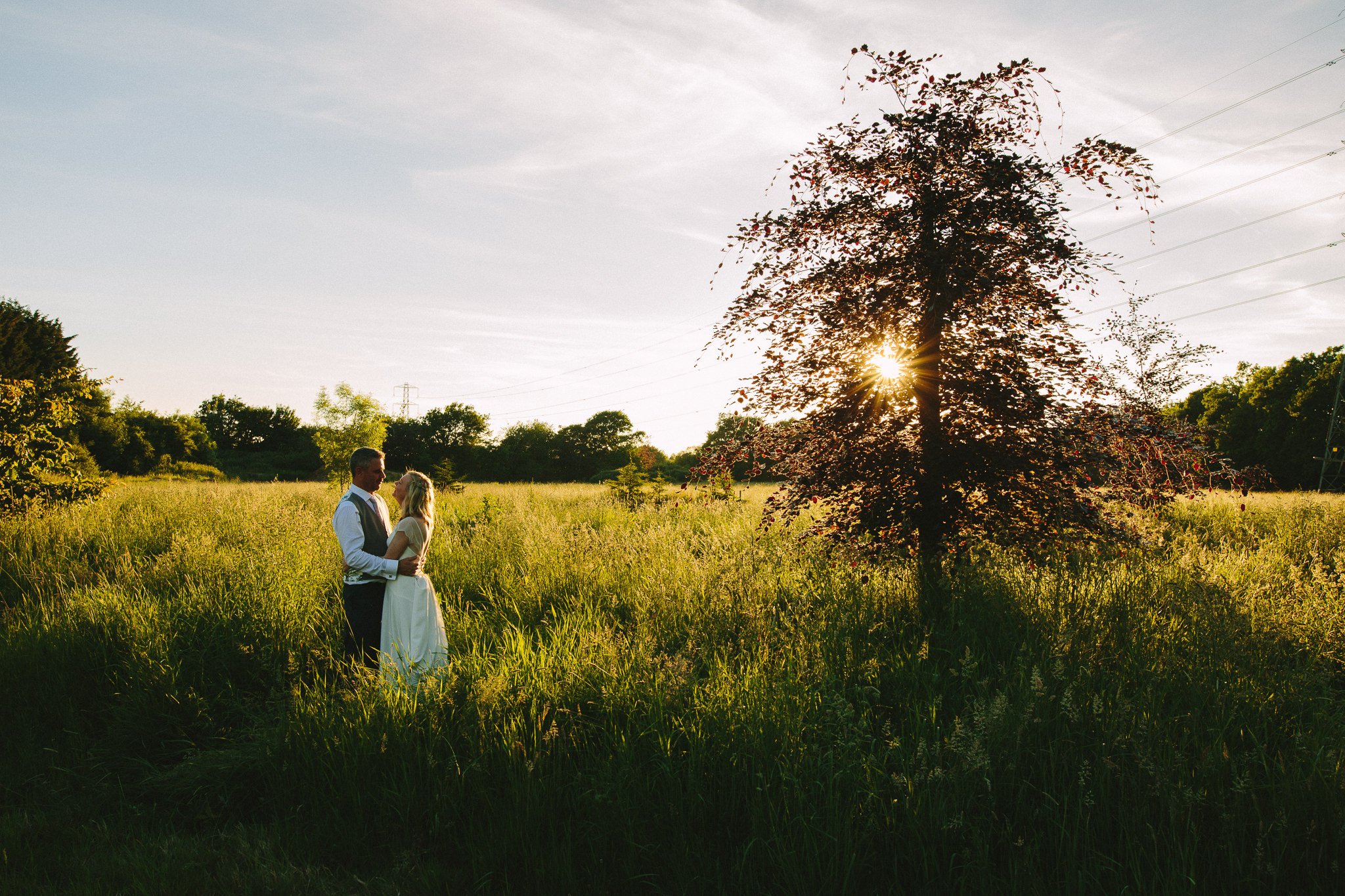  Bride and Groom stand in a field next to a tree at Rivervale Barn 