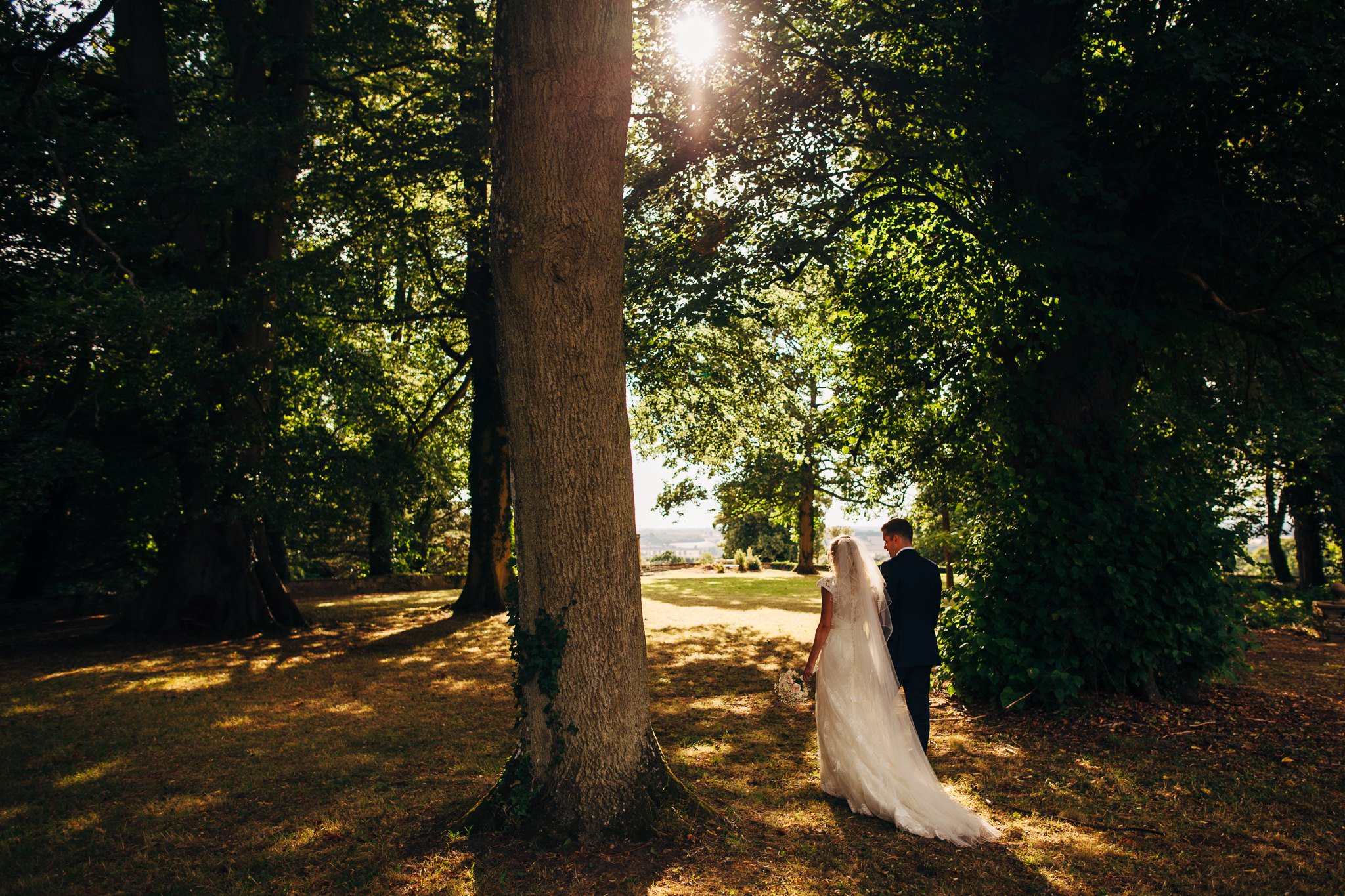  Bride groom walk through a wooded area of Aynhoe Park 