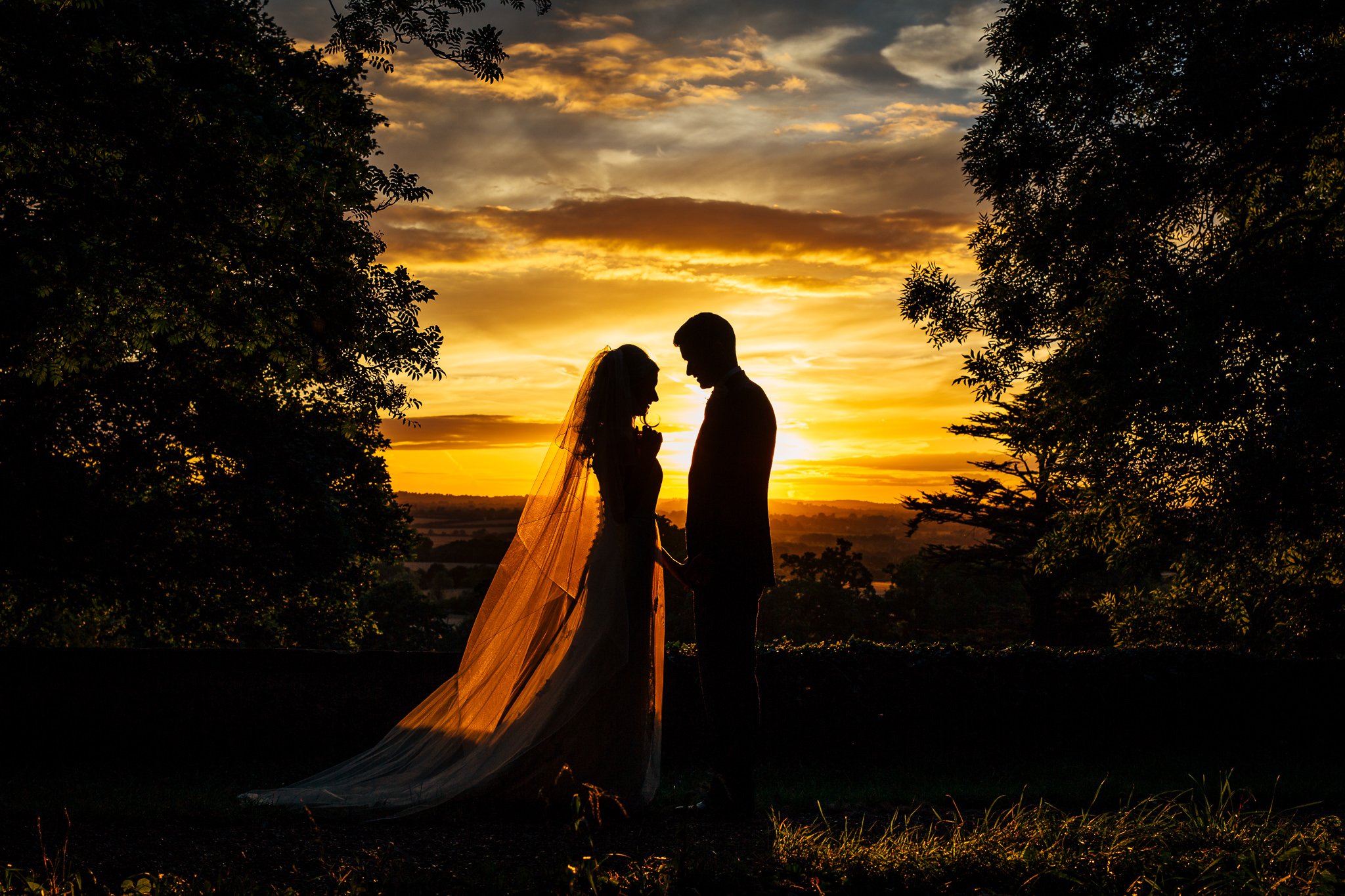  Bride and groom in silhouette with the sun setting behind them at Aynhoe Park 