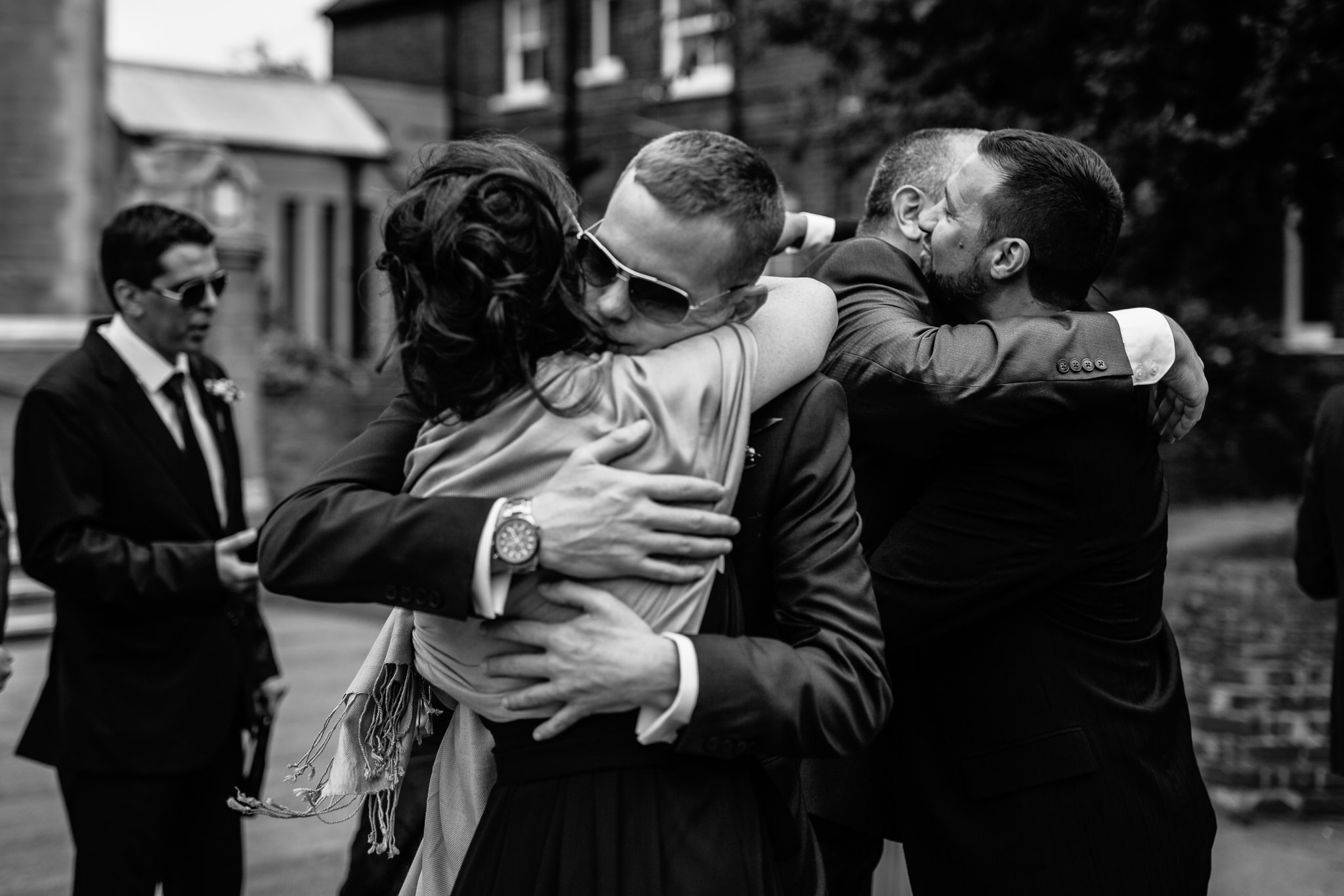  Groom hugs wedding guest outside Ealing Abbey 