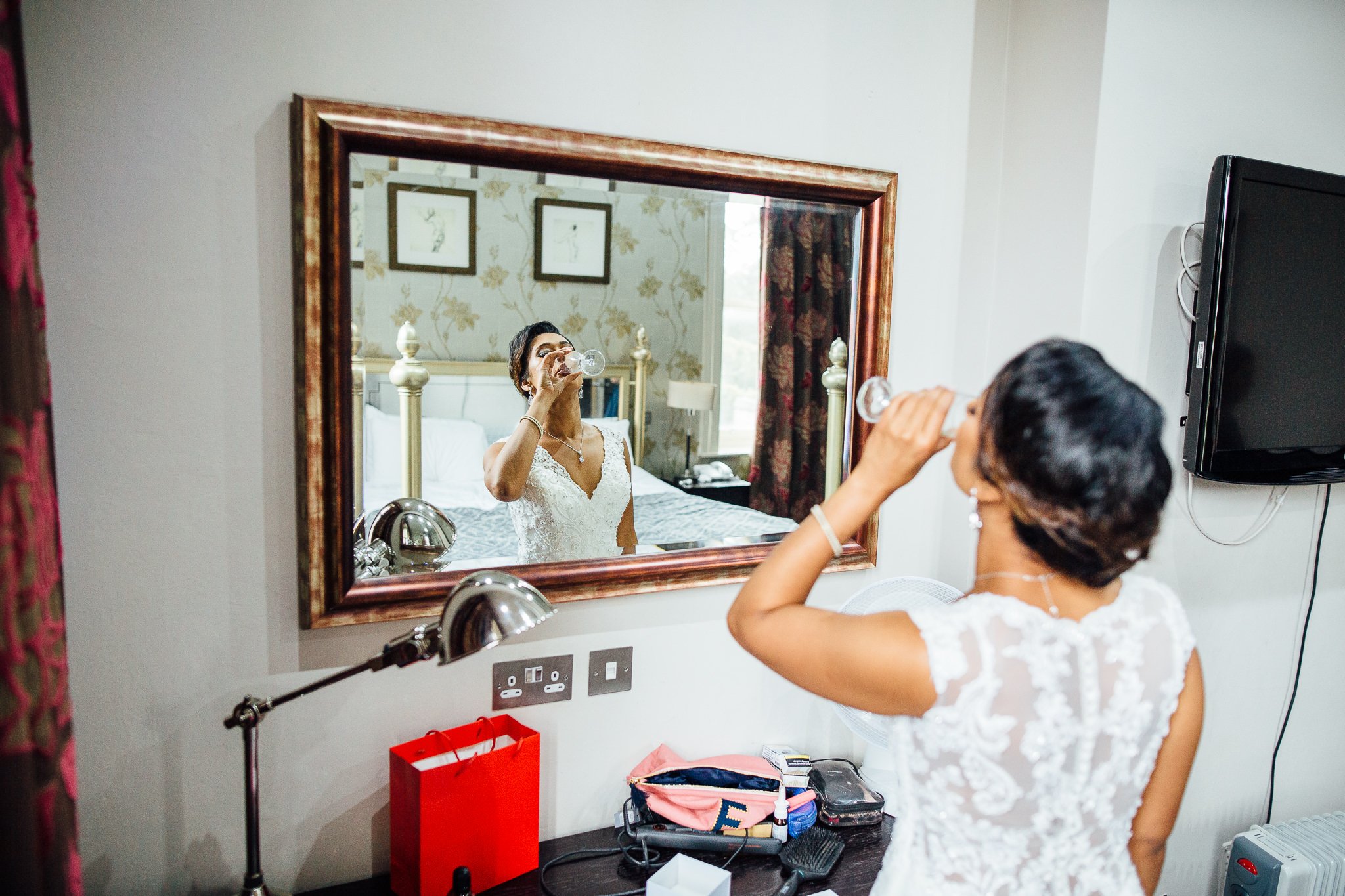  Bride drinking a glass of champagne at Coulsdon Manor Hotel 