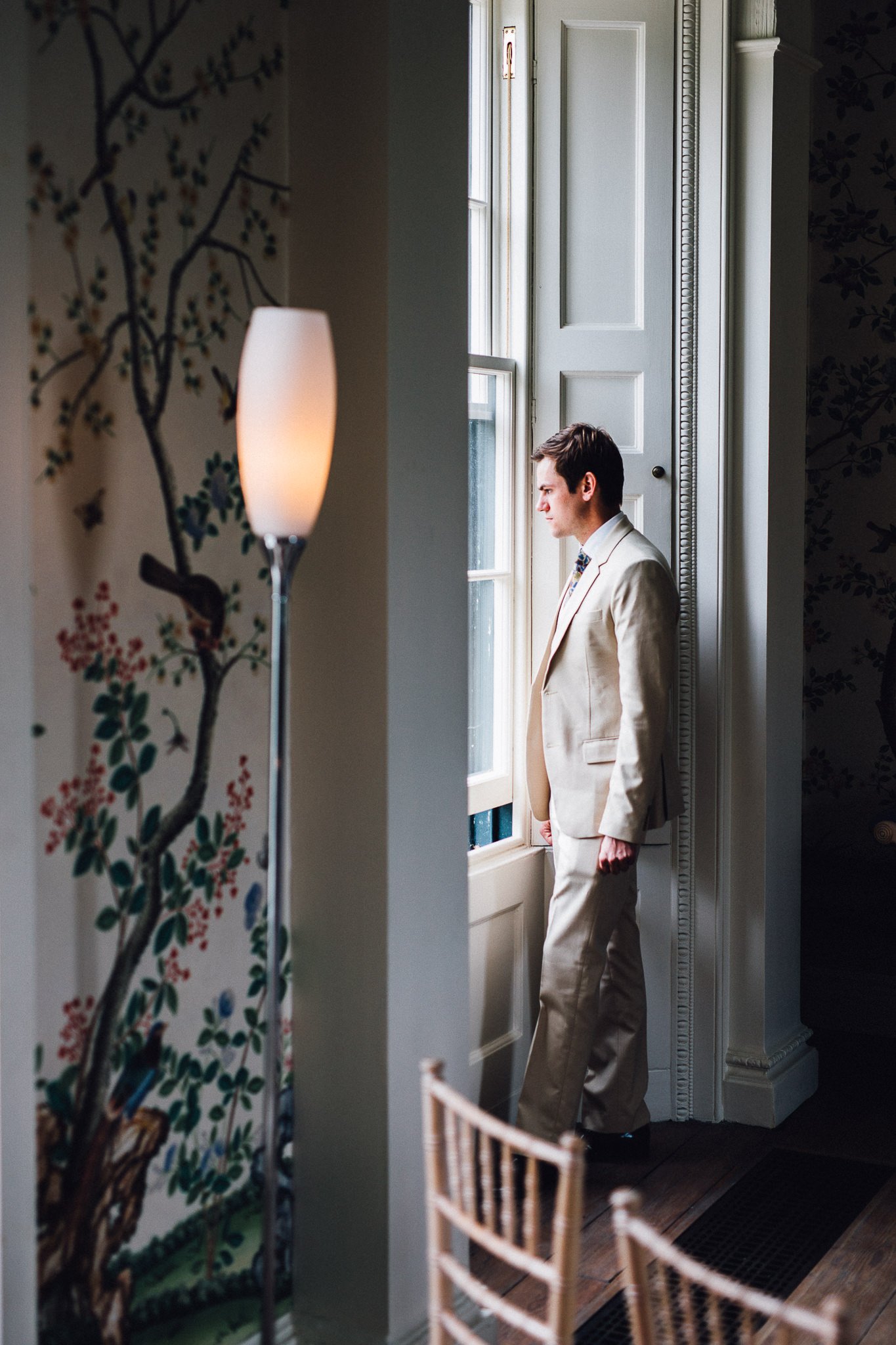  Wedding guest looks out of a window waiting for the bride to arrive at  Pitzhanger Manor 