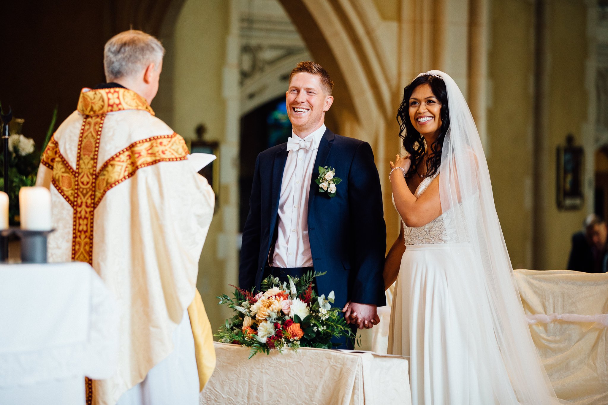  Bride and Groom smiling during the ceremony at Ealing Abbey 