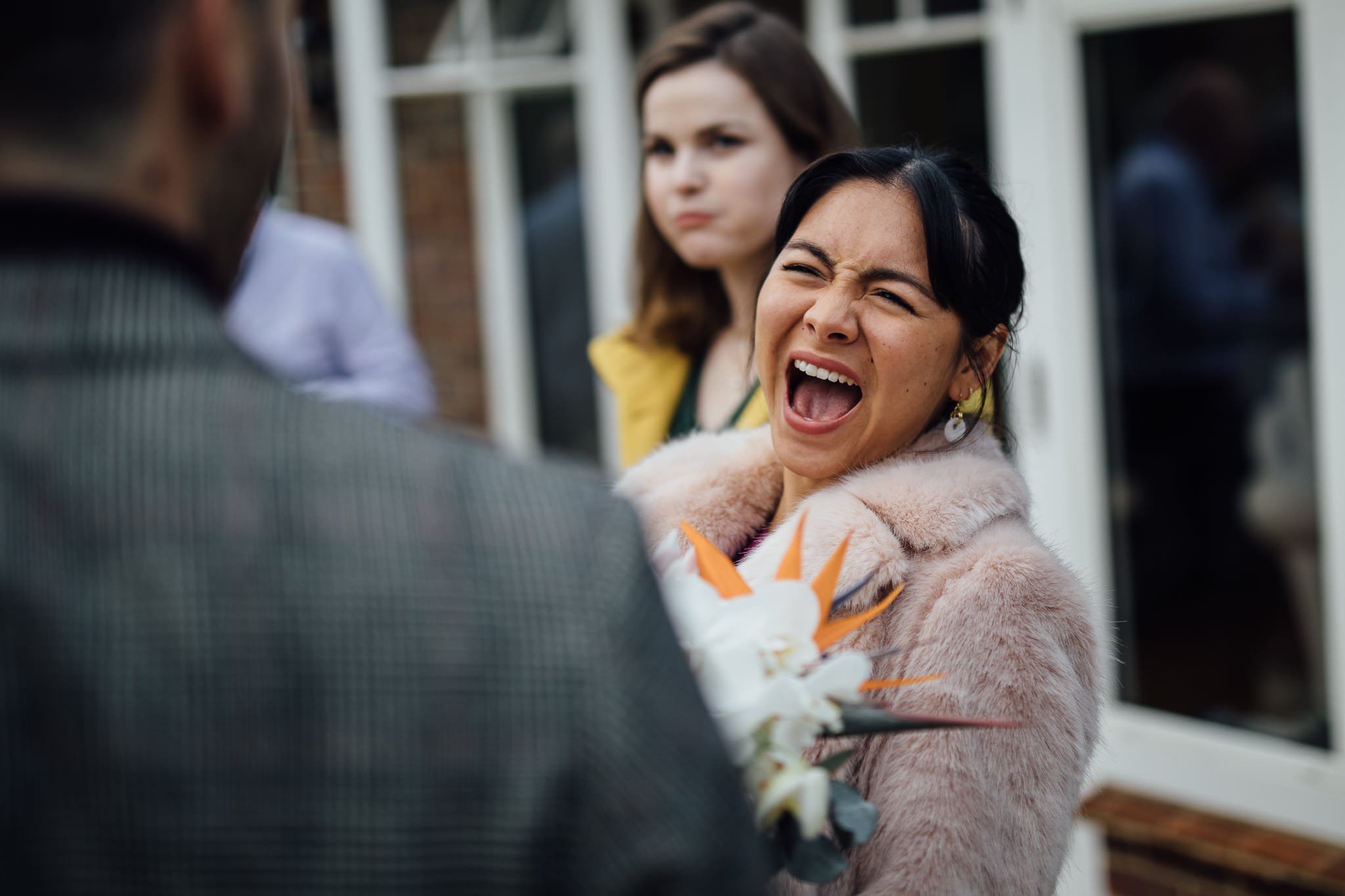  Wedding guest laughing after the wedding ceremony at The Mansion in Leatherhead 