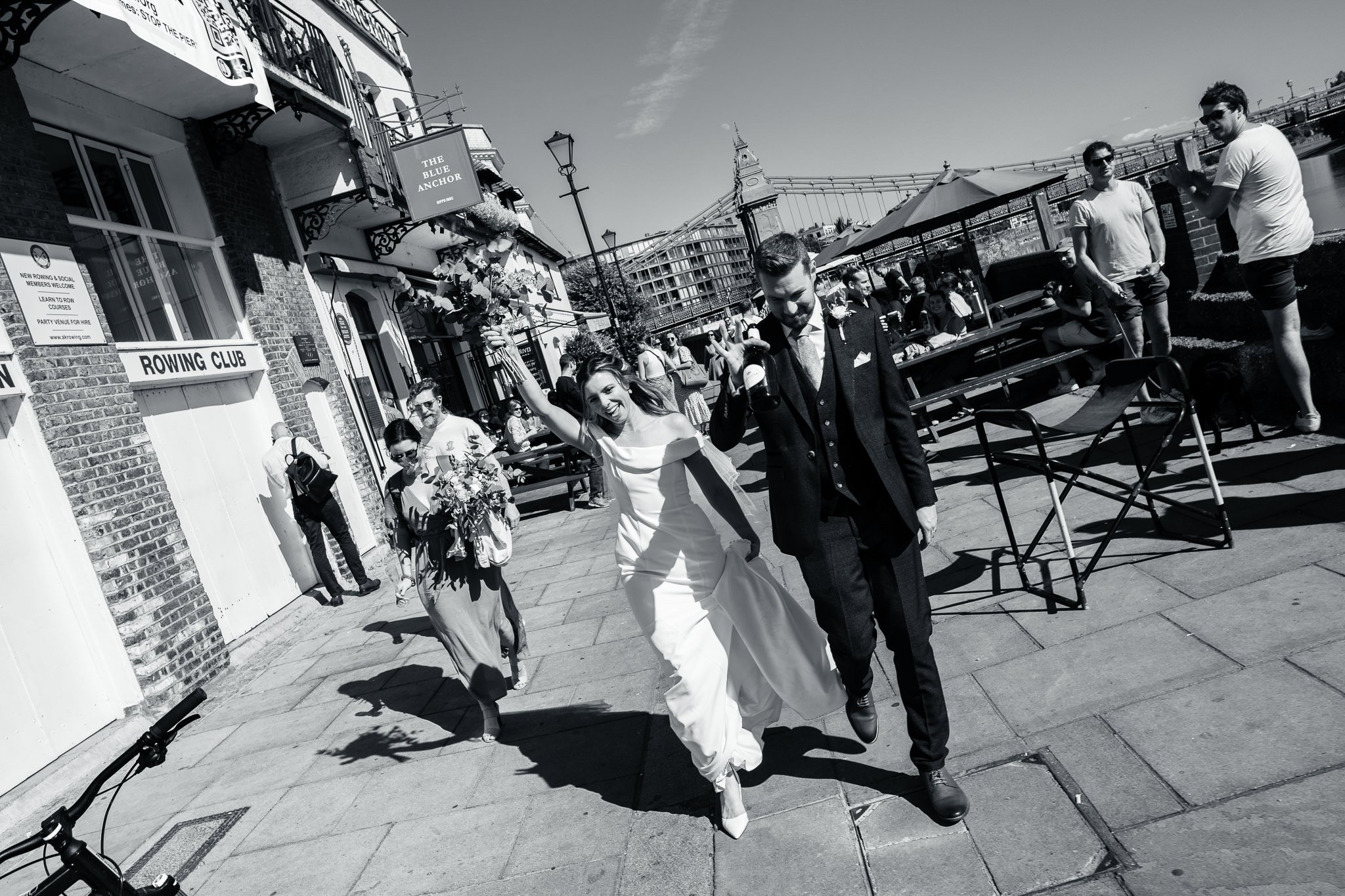  Bride and Groom celebrating as they walk past the Blue Anchor pub next to the River Thames 