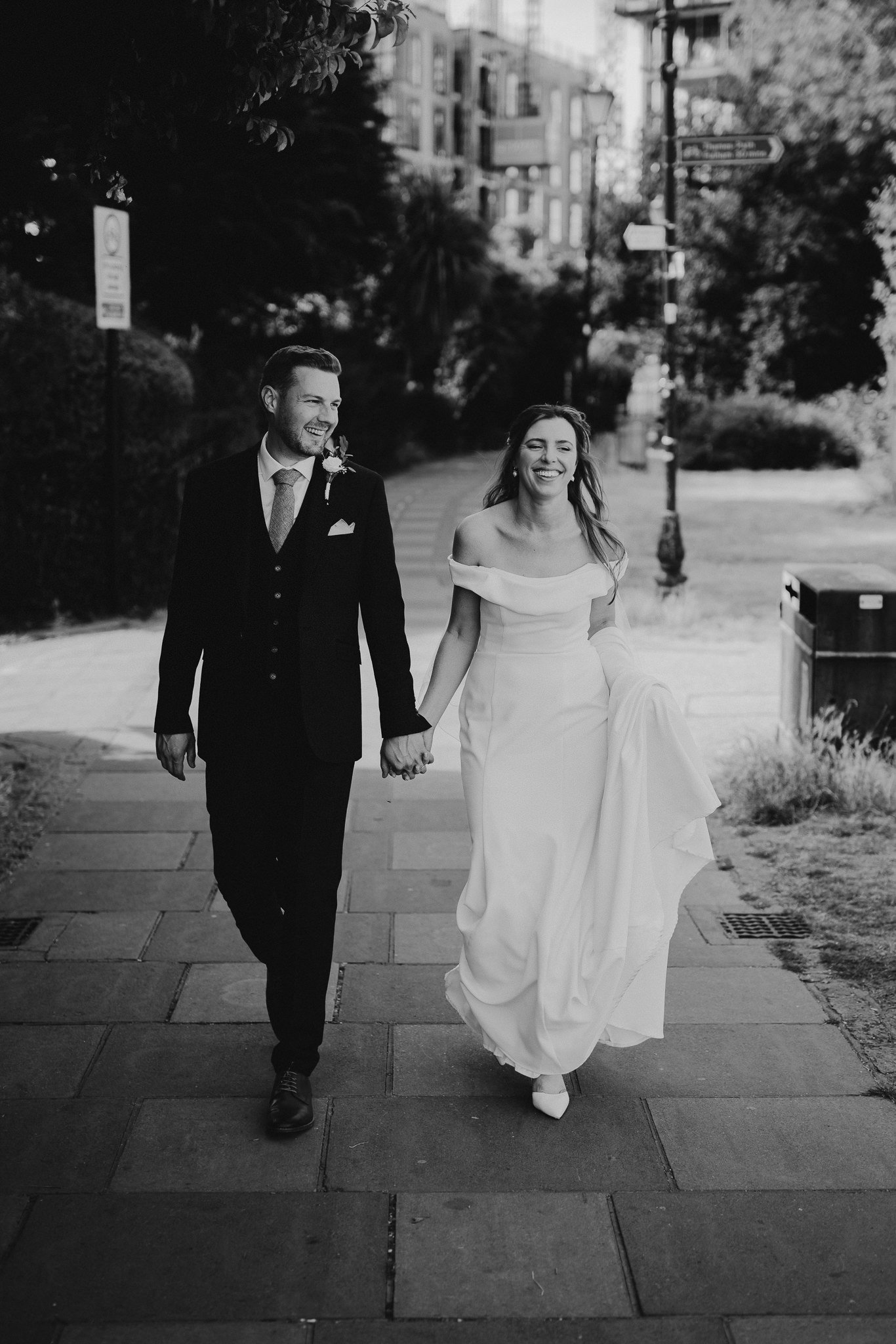  Bride and Groom walk hand in hand next to the River Thames in Hammersmith 