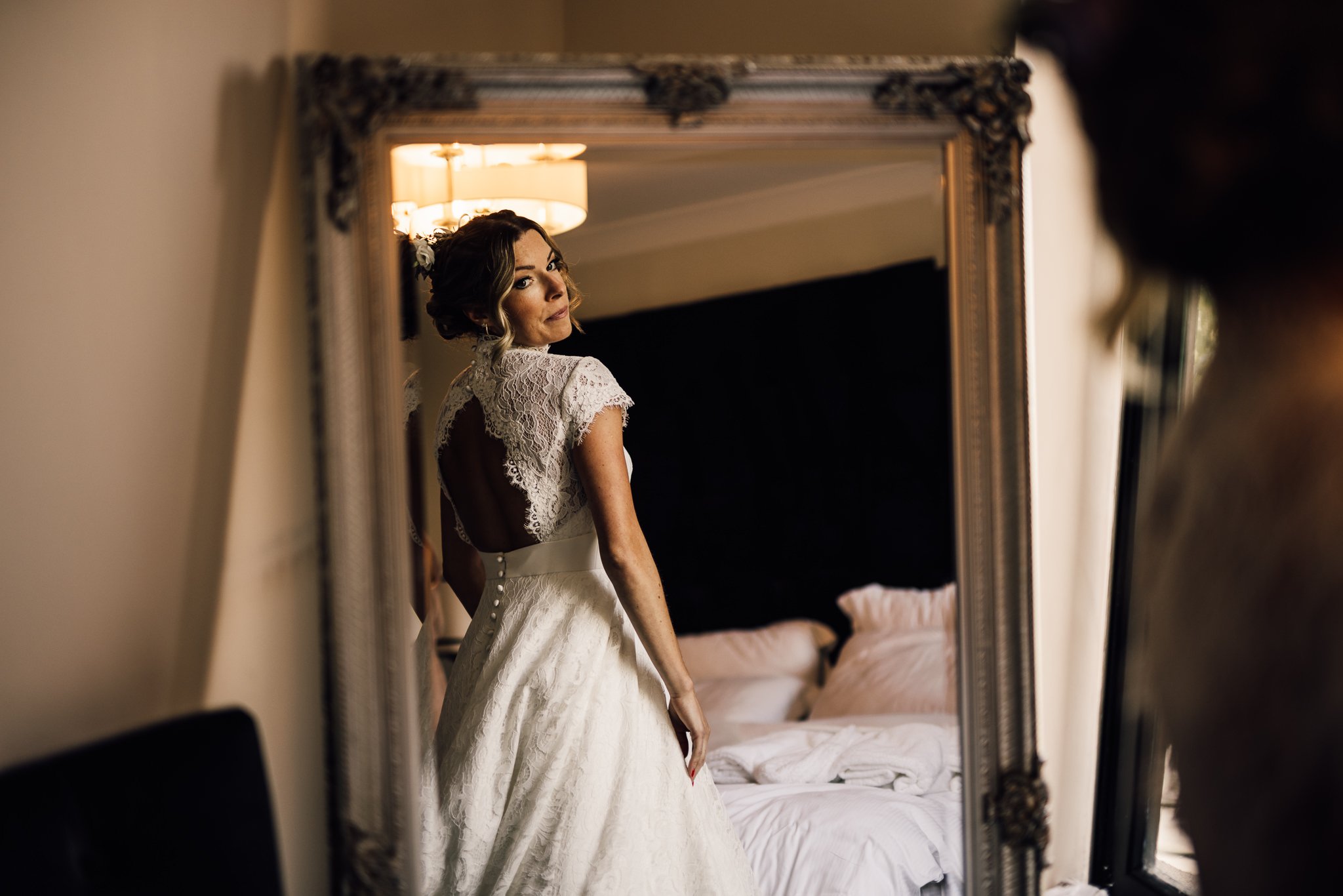  Bride looks at the back of her wedding dress in the mirror 