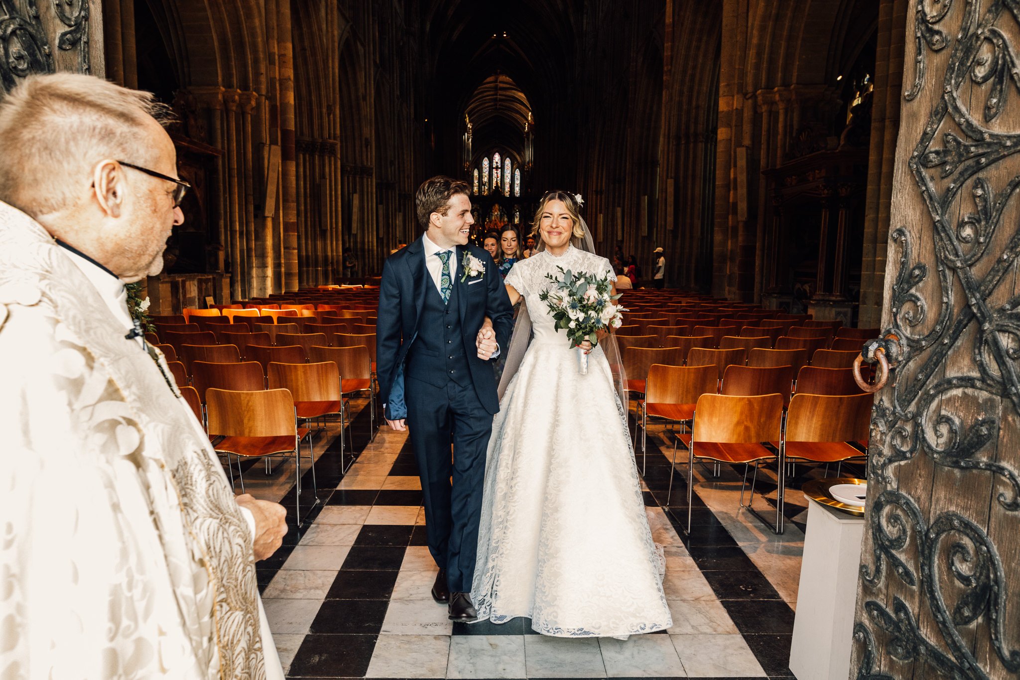  Bride and Groom walk out of Worcester Cathedral after getting married 