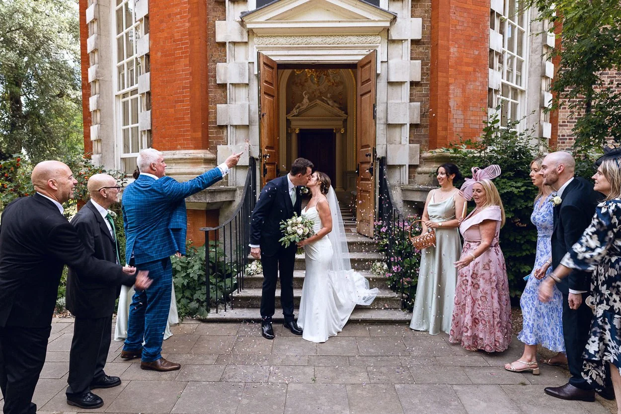 Bride and Groom kiss whilst having confetti thrown at them