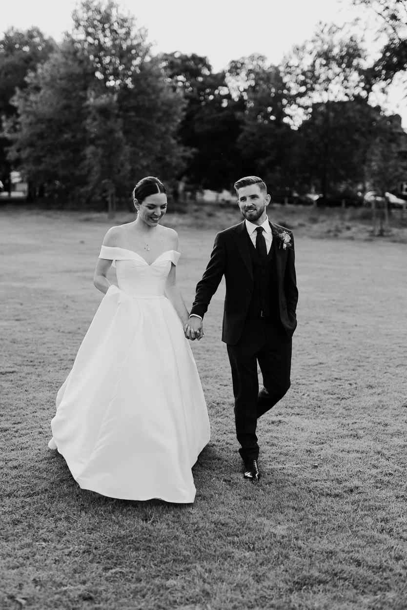 Bride and Groom walk across Ealing common hand in hand