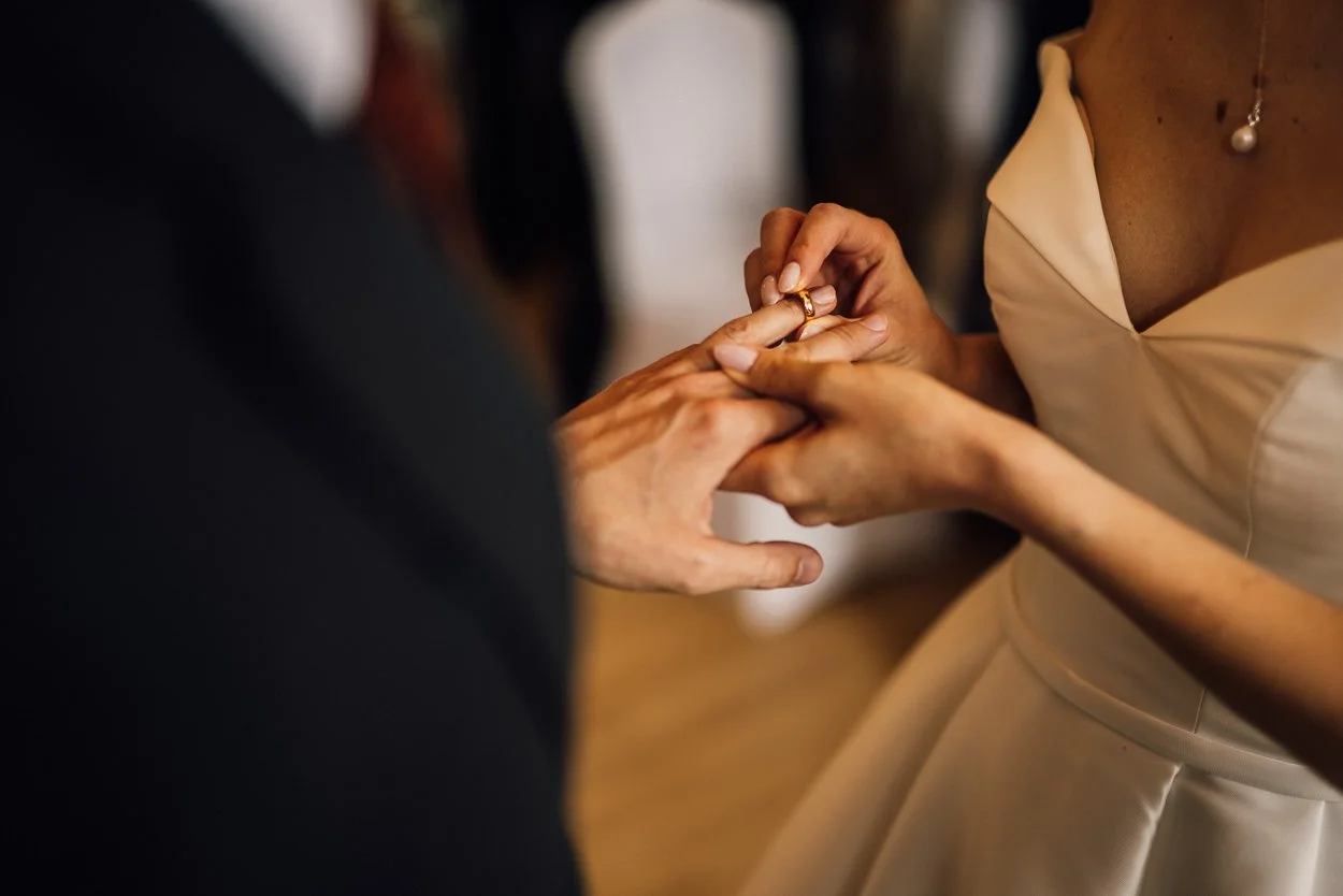 Bride placing wedding ring on grooms finger