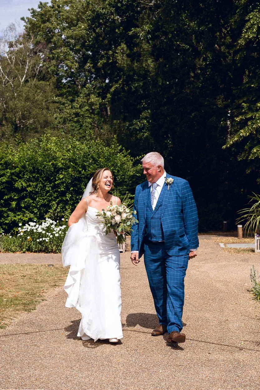 The bride and her father laughing as they walk into New Orleans House Gallery