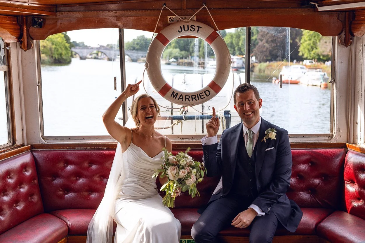 Bride and Groom point at a just married sign