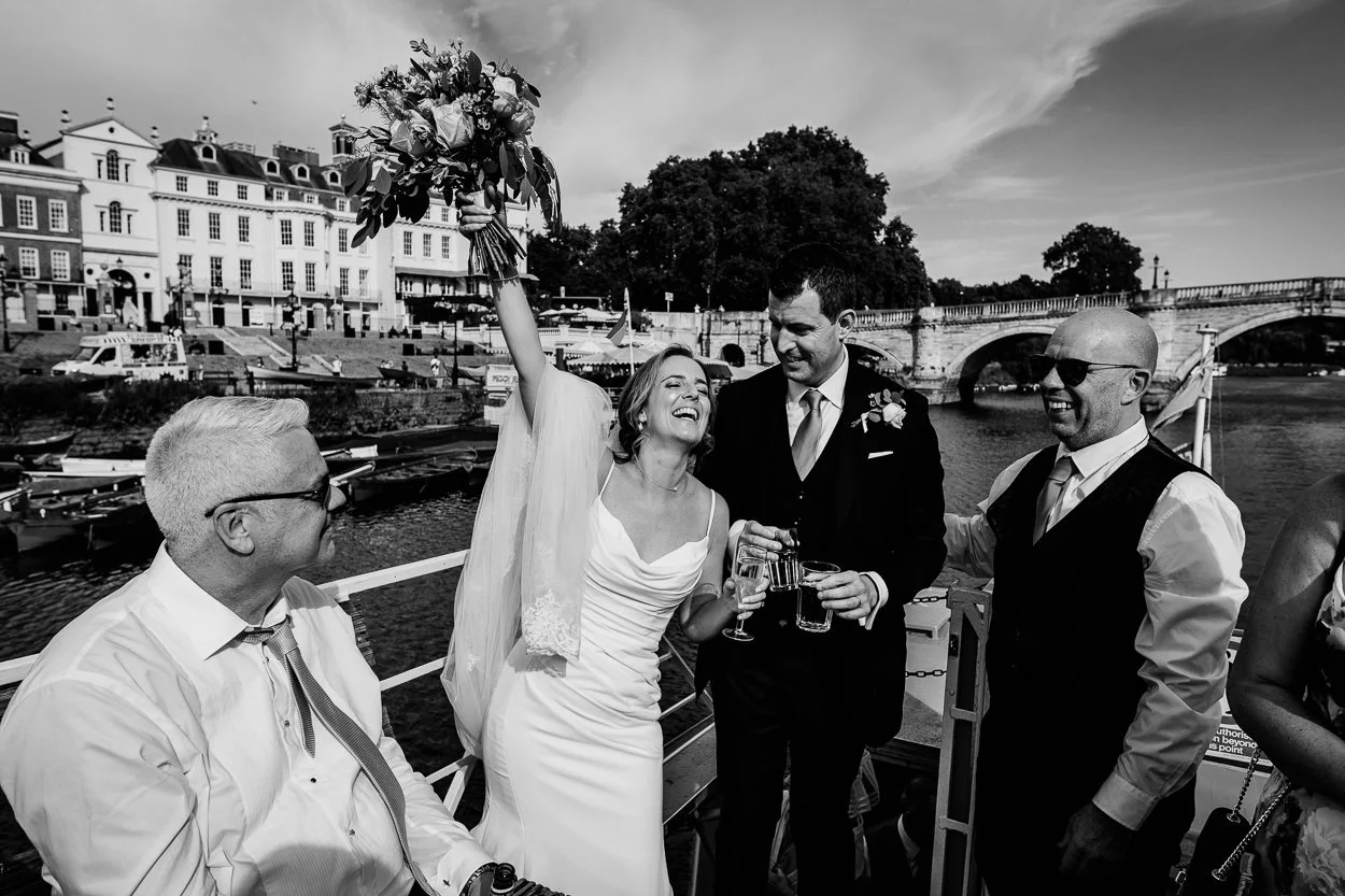 Bride celebrating on a boat on the thames with Richmond in the background