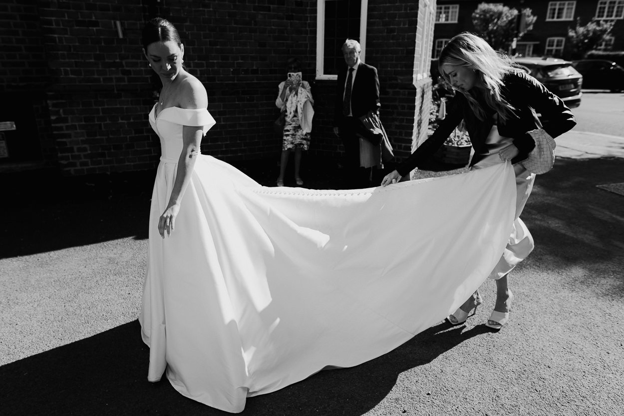 Bridesmaid adjusts bride's dress