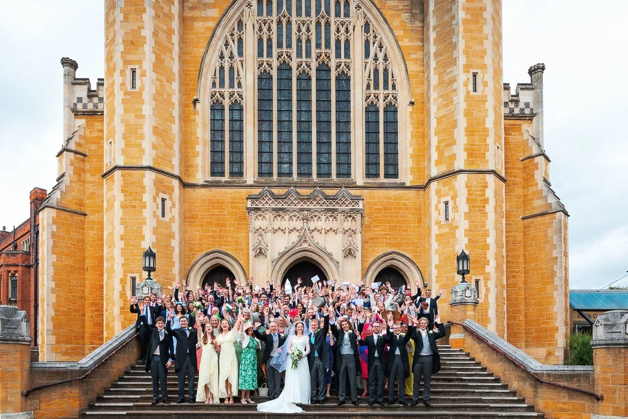 Group photograph of all wedding guests on the steps of Ealing Abbey