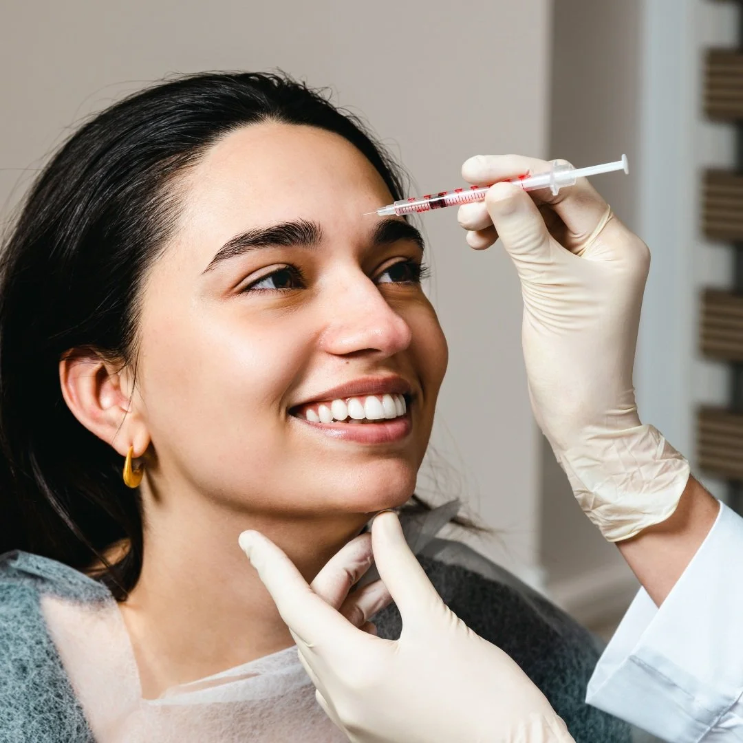 Smiling young woman receiving Botox injections in the forehead