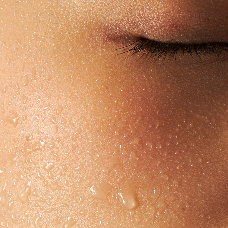 Close-up of healthy glowing skin with water droplets illustrating the oil-in-water skincare method
