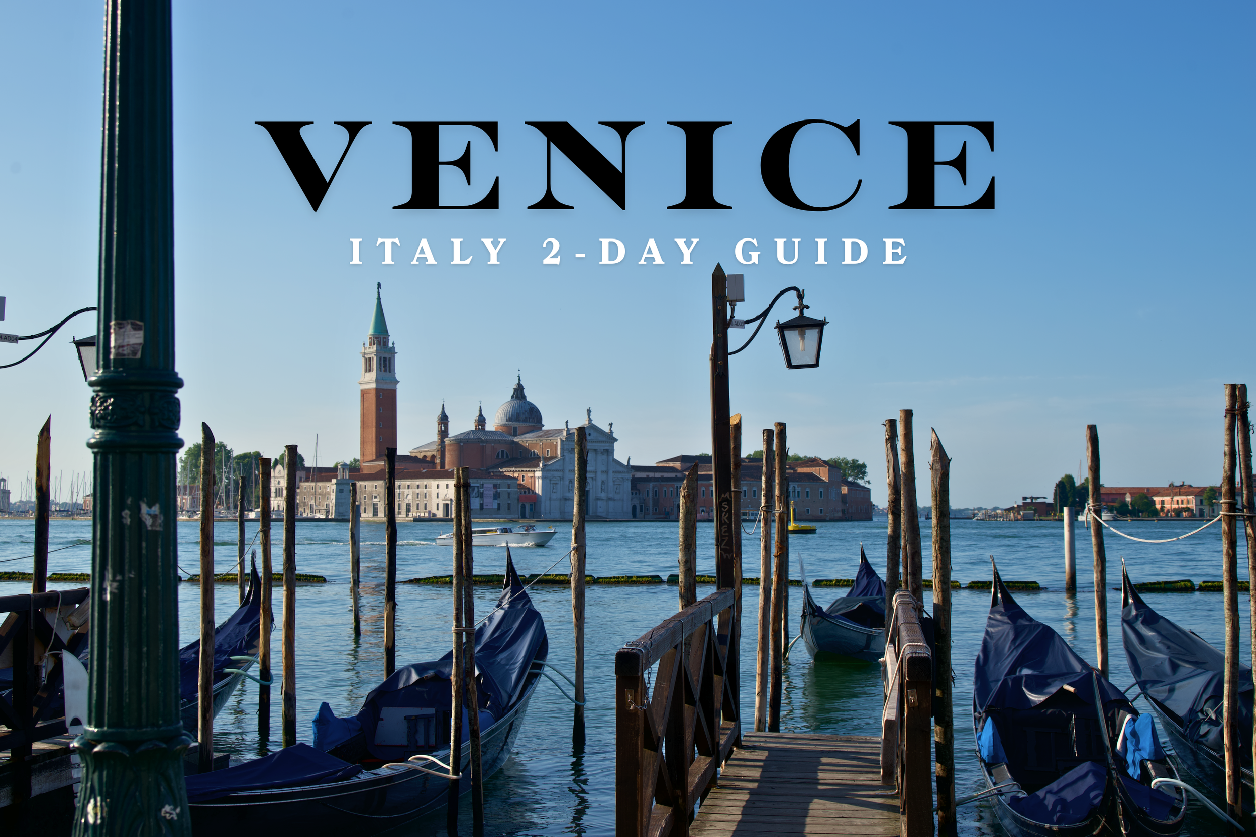 A view of gondolas docked at a pier in Venice, Italy, with the Church of San Giorgio Maggiore in the background and the blue sky overhead.