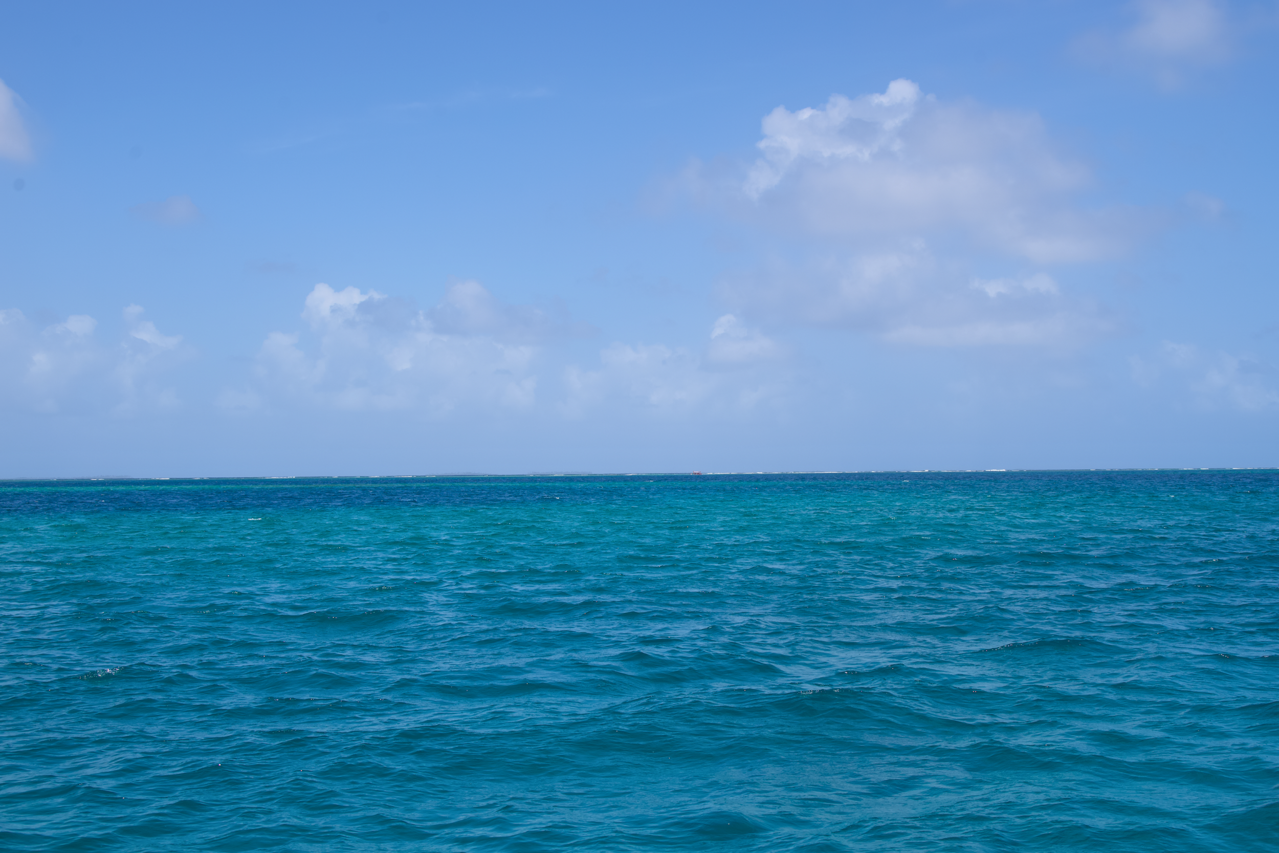Calm ocean with blue waters under a partly cloudy sky.
