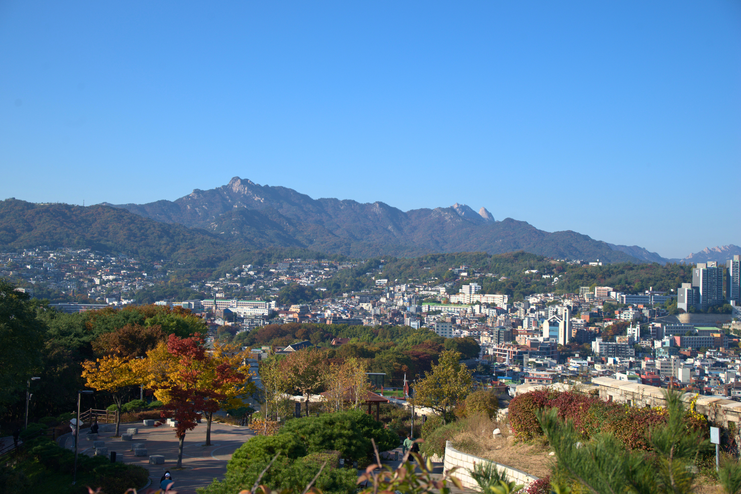 Seoul South Korea cityscape with modern skyscrapers and traditional hanok rooftops and mountain views during the fall