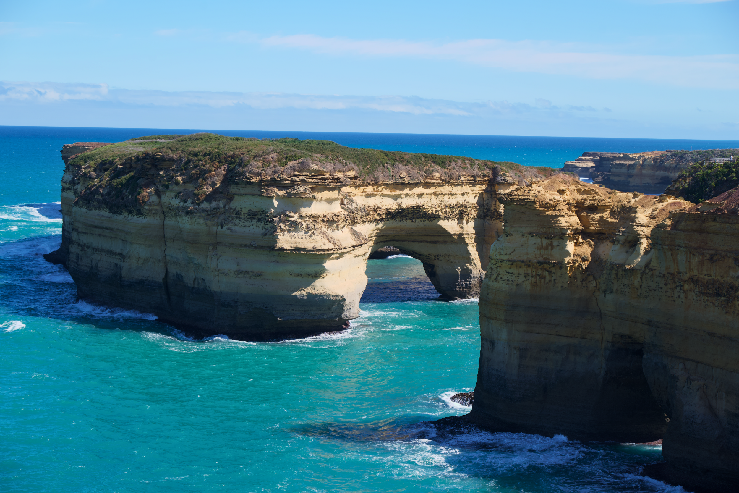 Cliffs with a natural arch formation over the ocean on a sunny day.